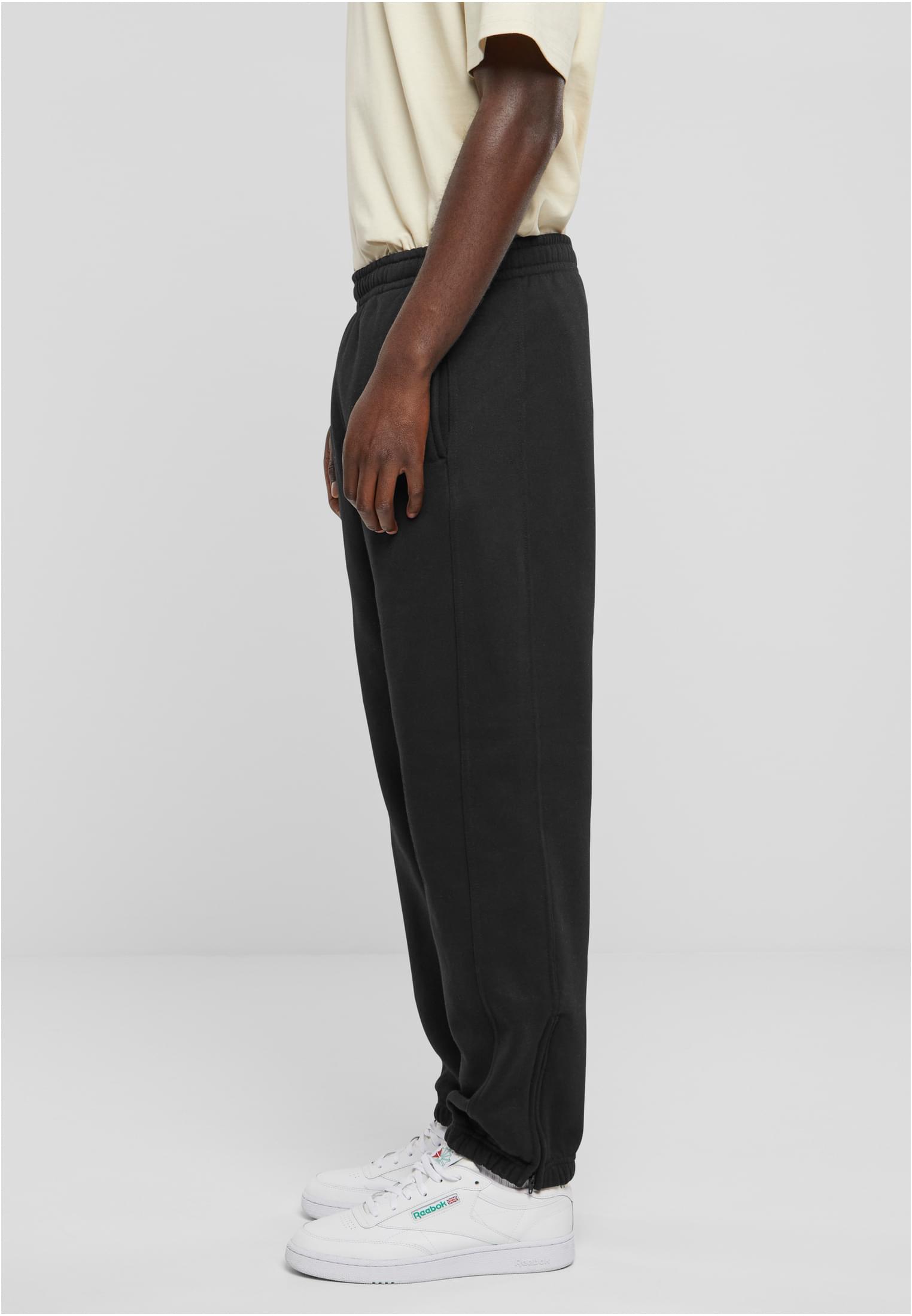 Sidovy av en man som bär svarta sweatpants och vita sneakers.