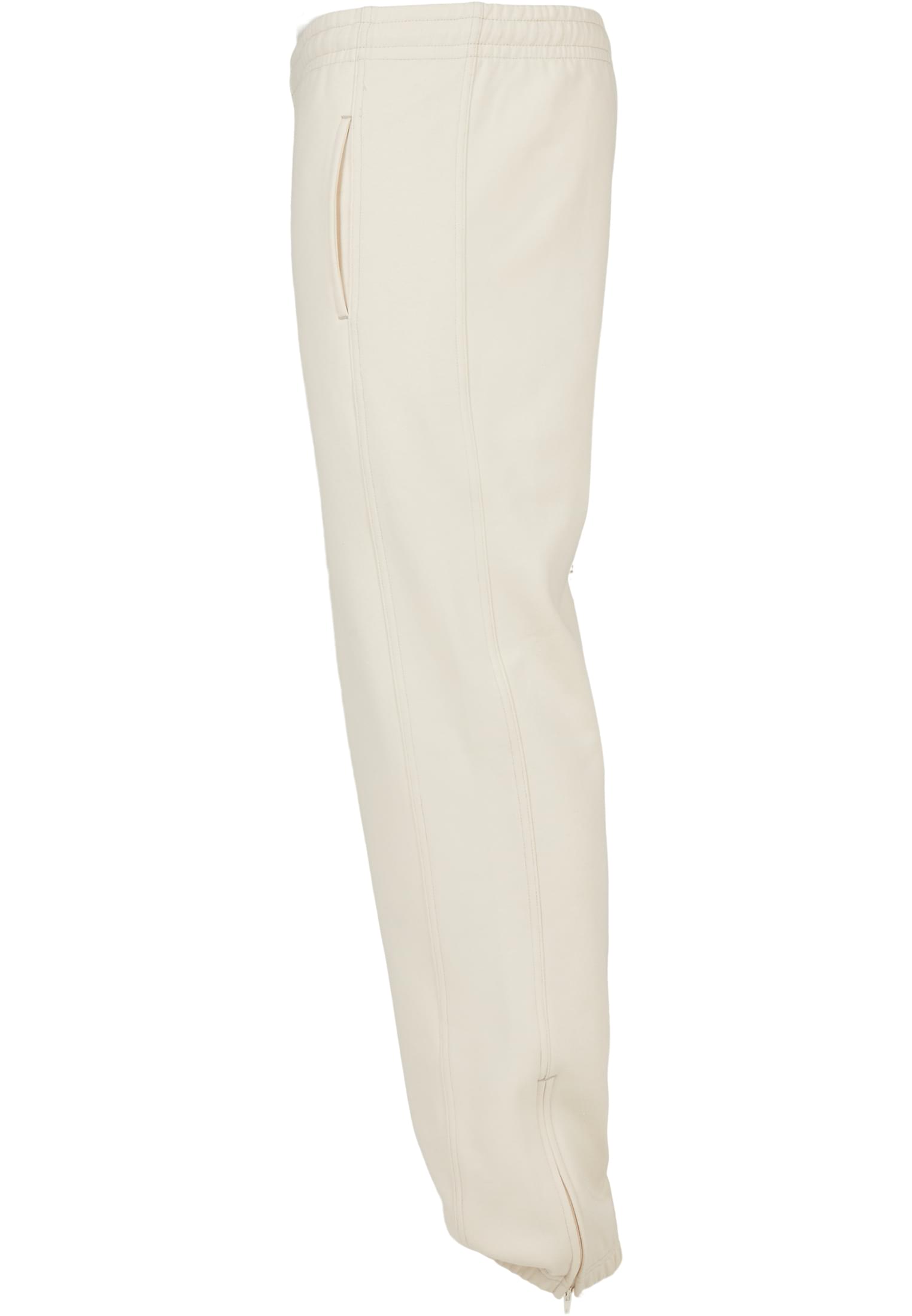 Sidoprofil av ett par ljusbeige UC Sweatpants, med fokus på midjan, fickan och dragkedjan vid benslutet.