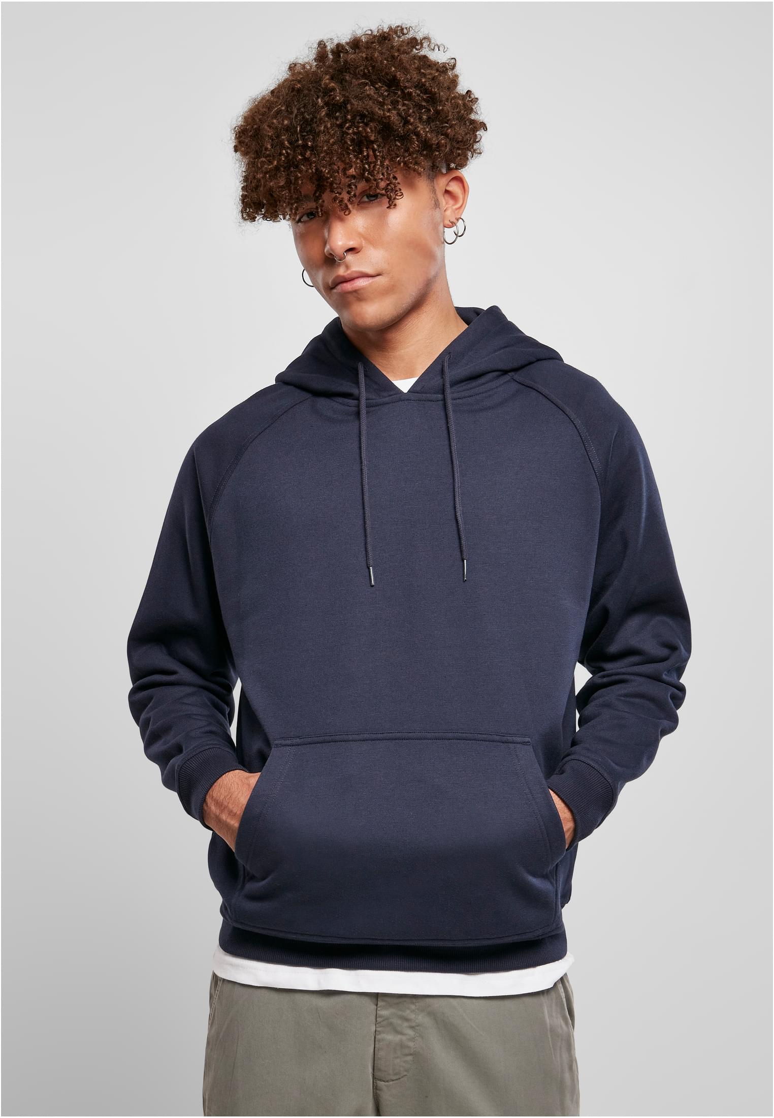 En manlig modell poserar framifrån i en mörkblå UC Blank Hoody med händerna i kängurufickan.