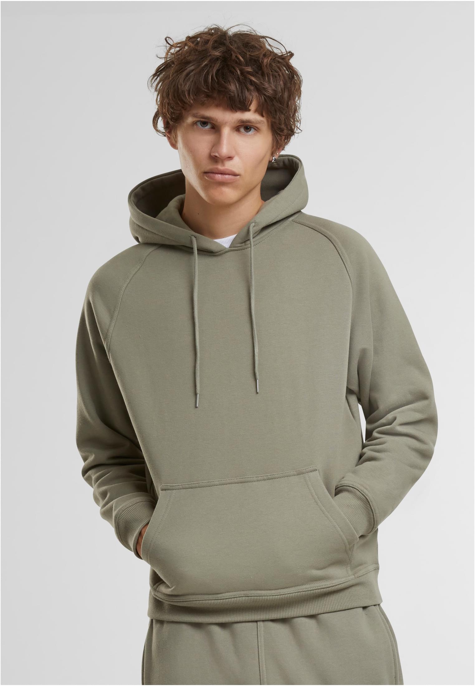 Manlig modell visar framsidan av en ljusgrön UC Blank Hoody, med händerna i kängurufickan.