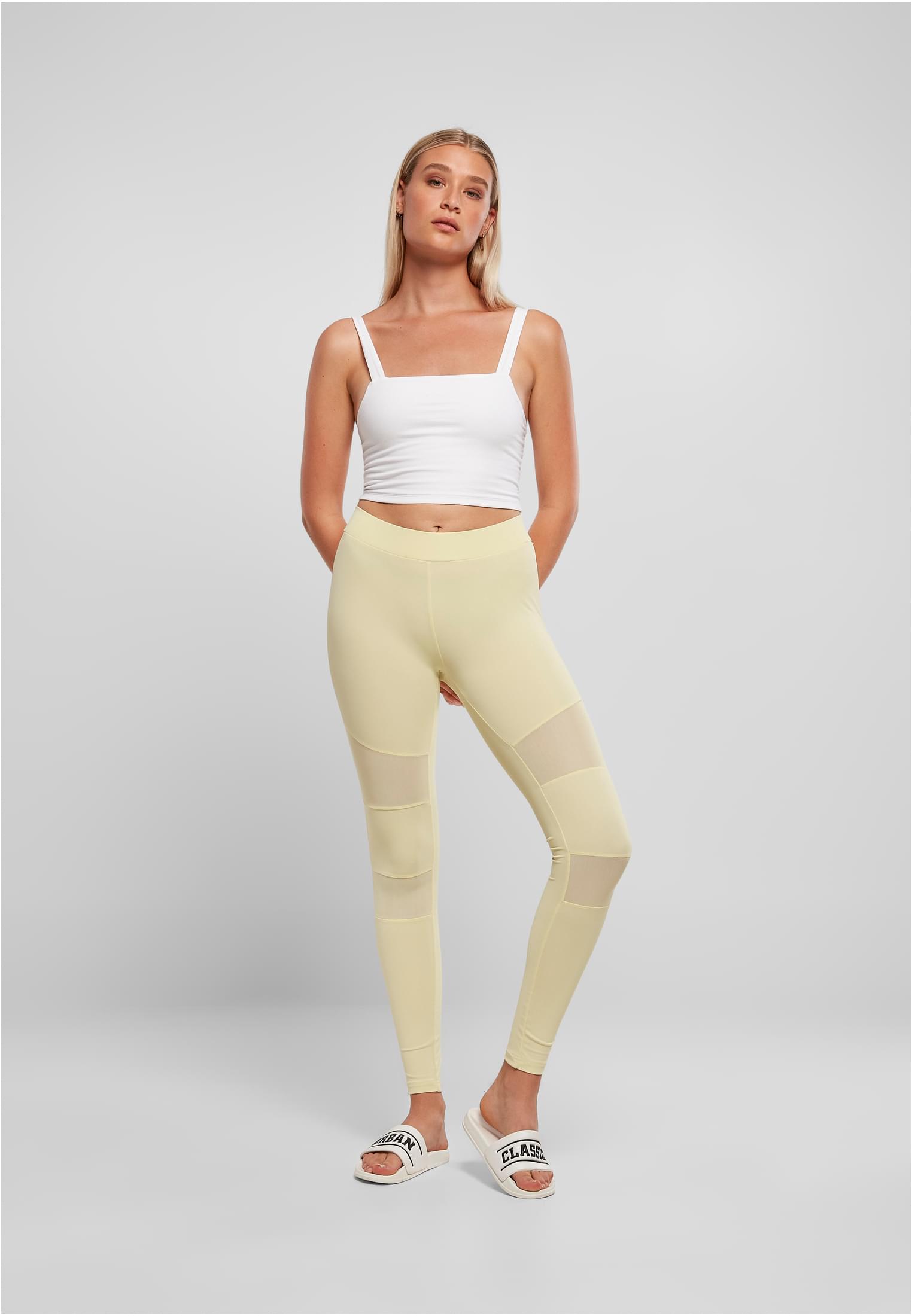 Kvinna som bär varmgrå Ladies Tech Mesh Leggings med genomskinliga meshpaneler, stylad med en vit crop top.