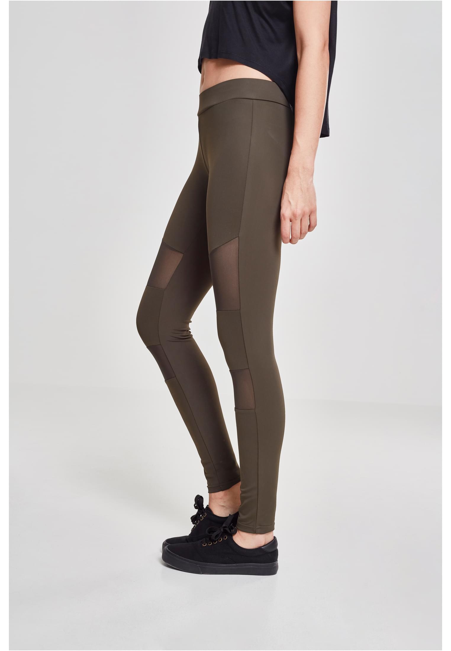 Sidovy av modell som bär Ladies Tech Mesh Leggings i färgen warmgrey, stylade med en svart topp och svarta sneakers.