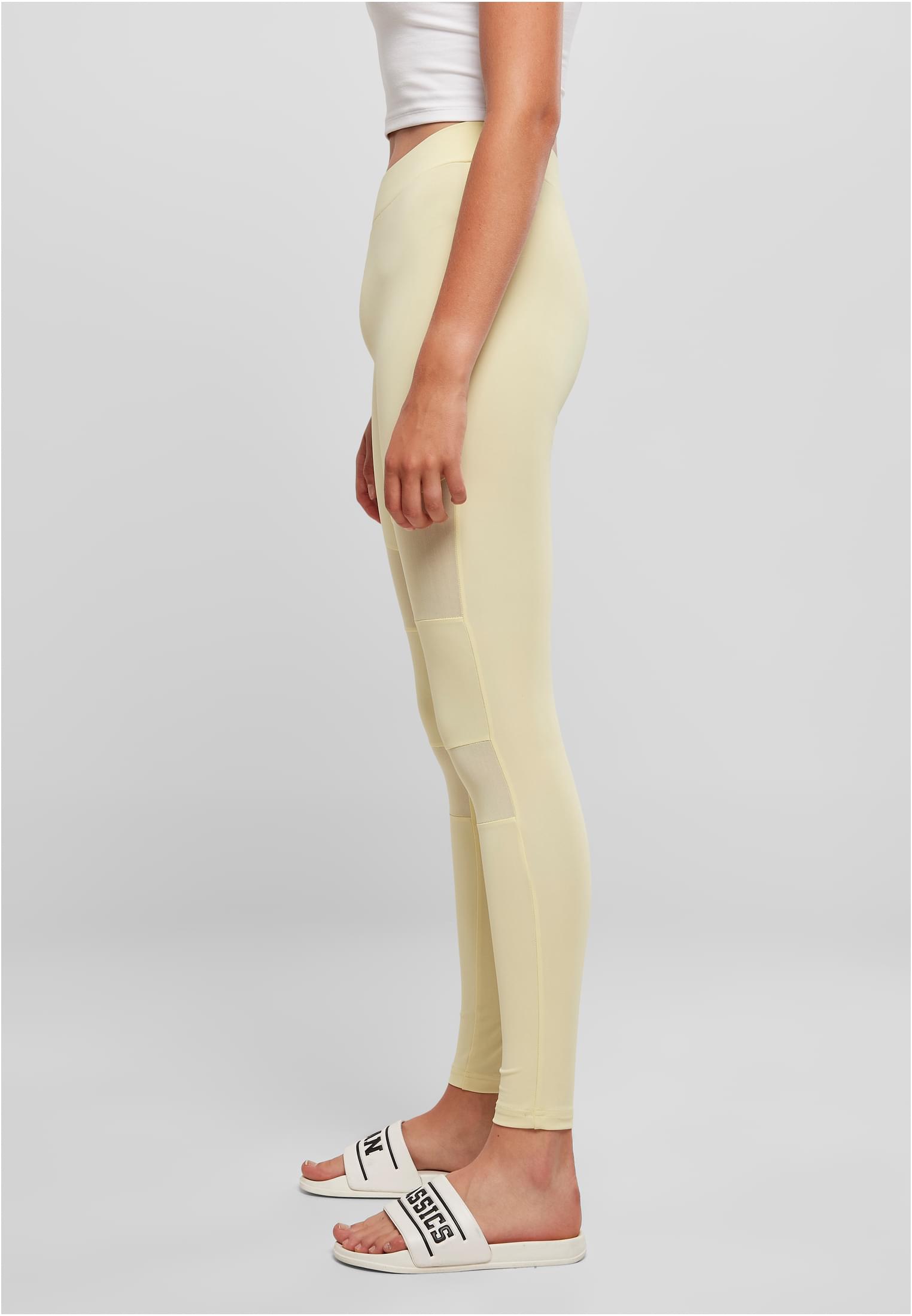 Sidovy av en kvinna som bär Ladies Tech Mesh Leggings med transparenta nätpaneler längs benen.