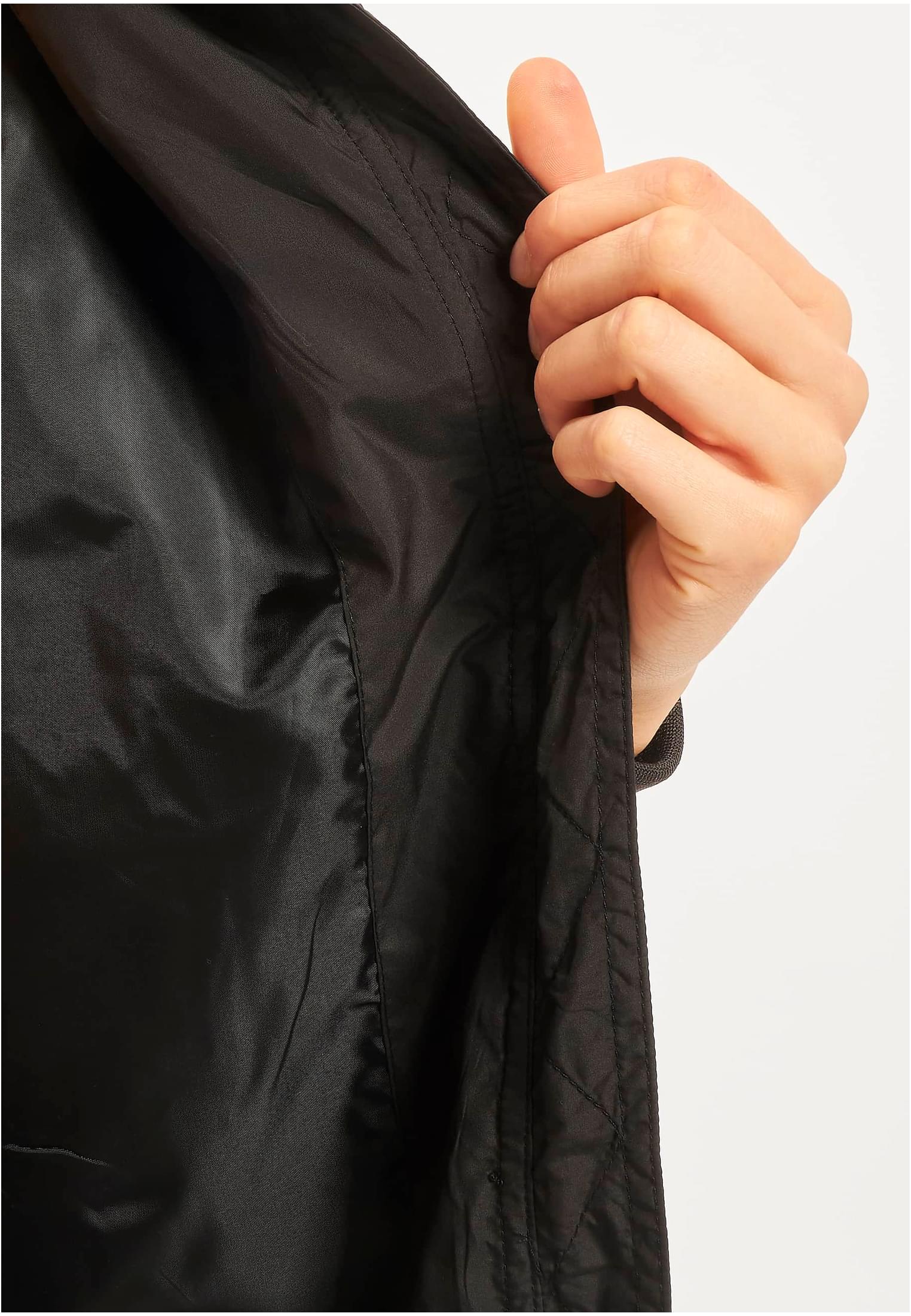 Detaljbild på en svart UC Light Bomber Jacket där en hand visar innerfodret.