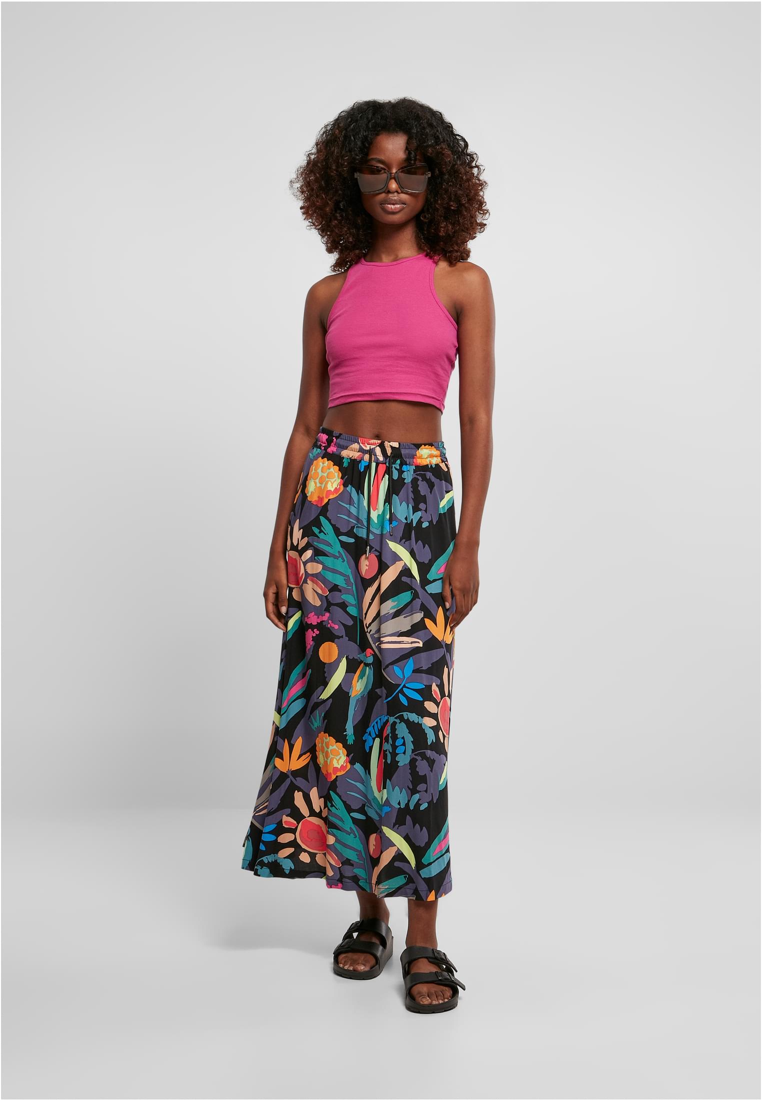 Modell som bär Ladies Cropped Rib Top i rosa, stylad med en mönstrad maxikjol och solglasögon.