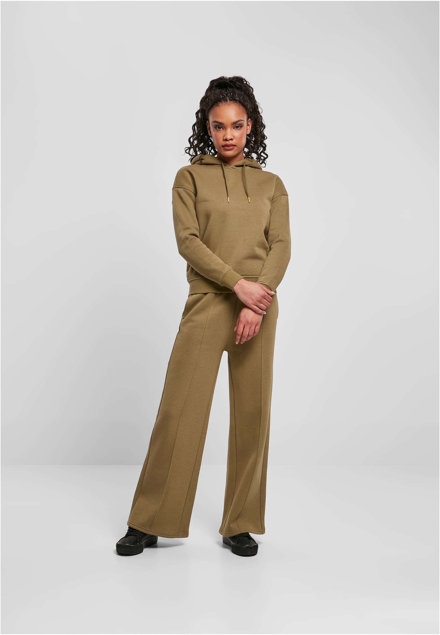 Kvinna som bär en komplett outfit från Urban Classics med en huvtröja och matchande byxor med vida ben i en mjuk, sjögräsgrön färg.