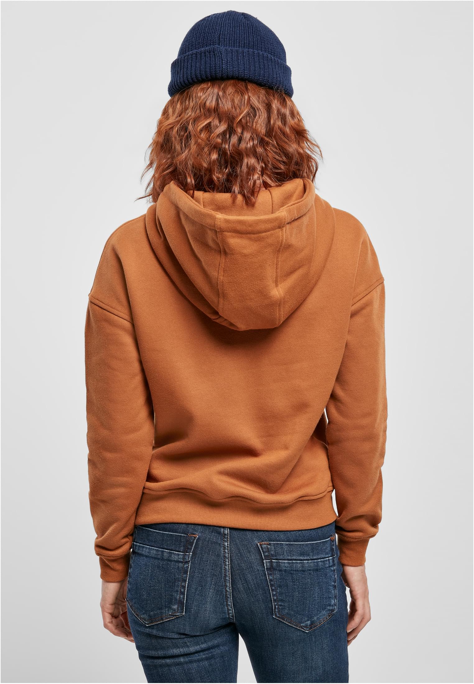 Kvinna sedd bakifrån som bär en brun Ladies Hoody, blå jeans och en blå mössa.