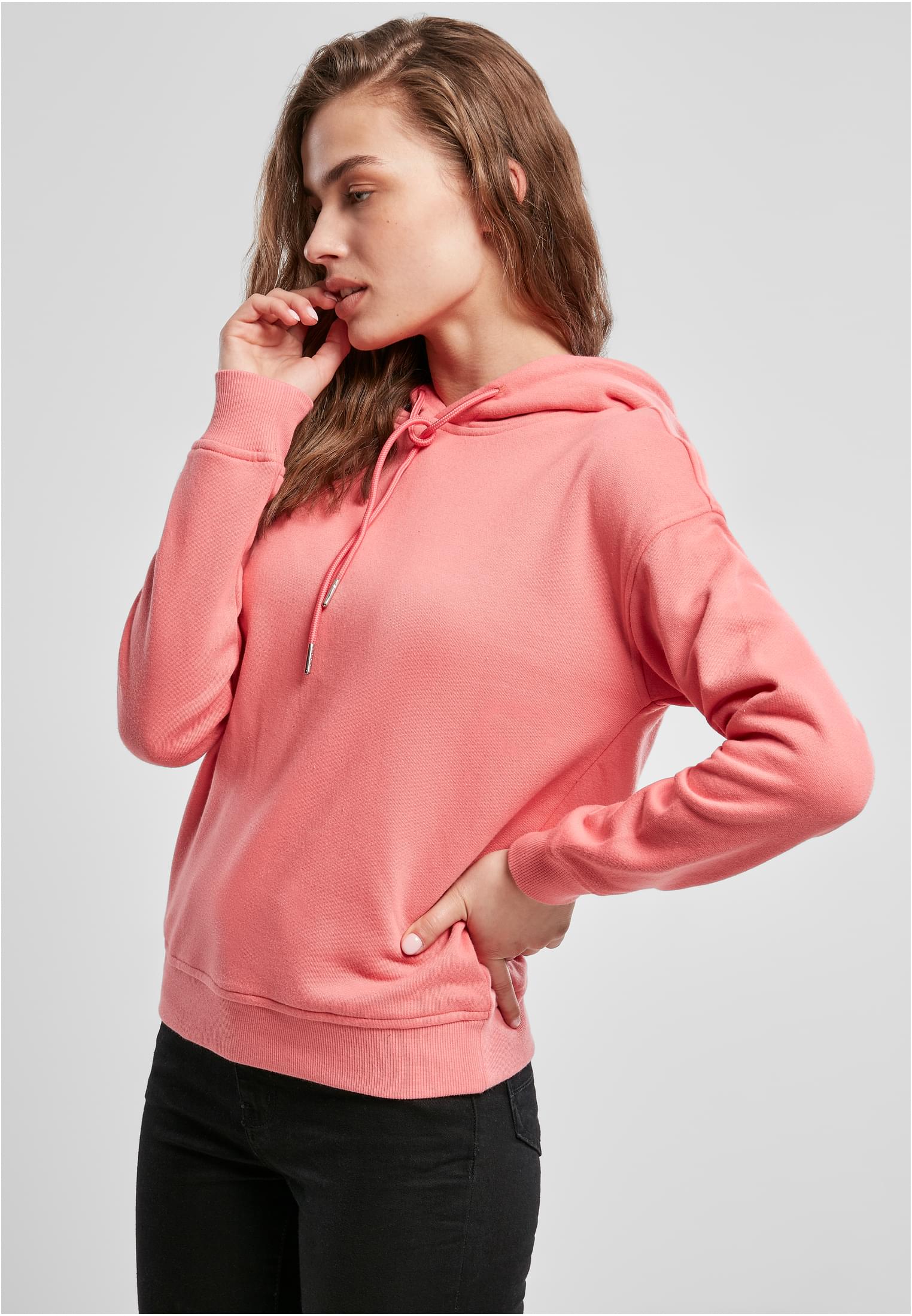 En kvinna som bär en rosa Ladies Hoody och svarta byxor, fotograferad snett framifrån.