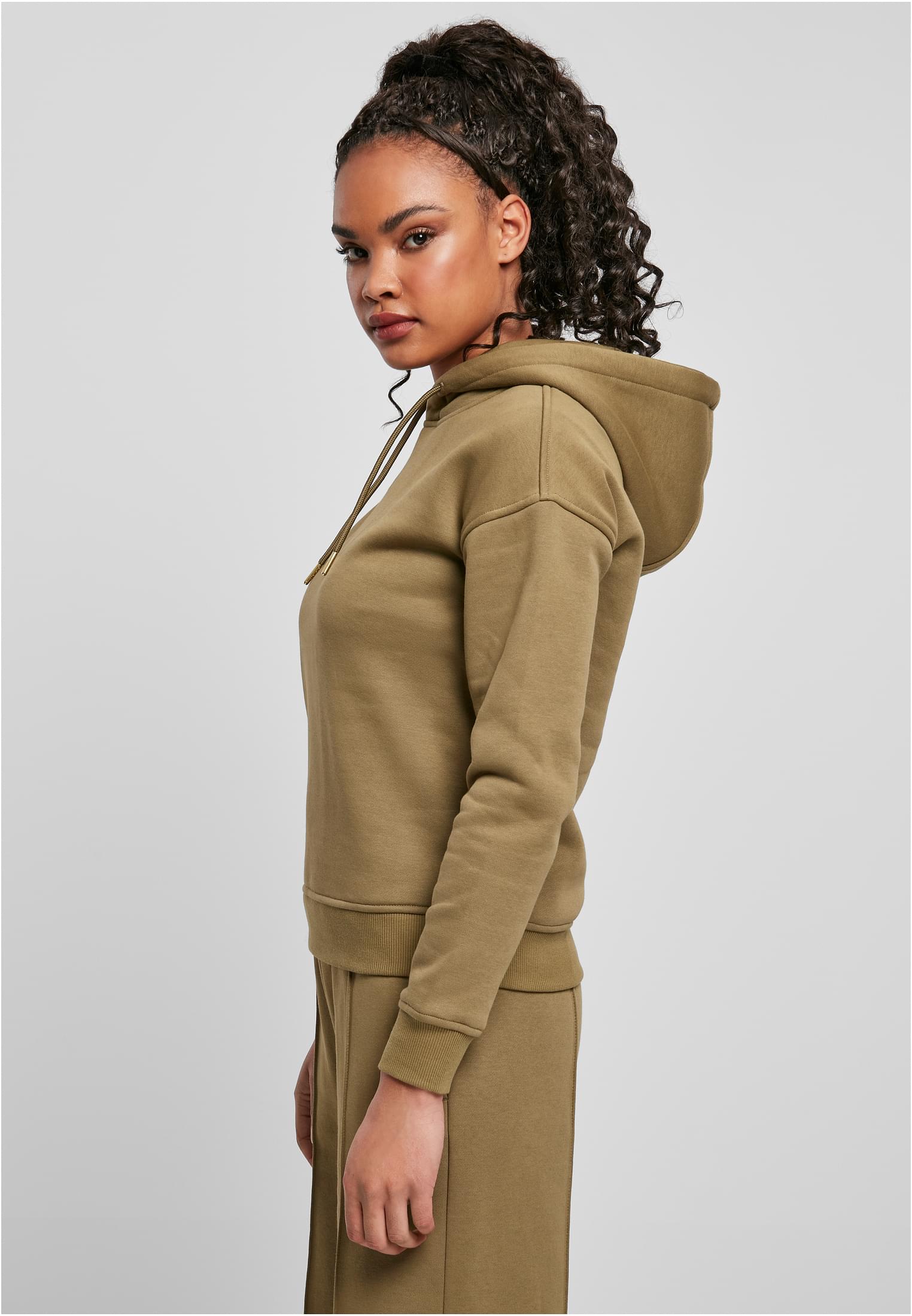 Sidovy av en modell som bär en mjukgrön UC Ladies Hoody med matchande byxor, mot en ljusgrå bakgrund.