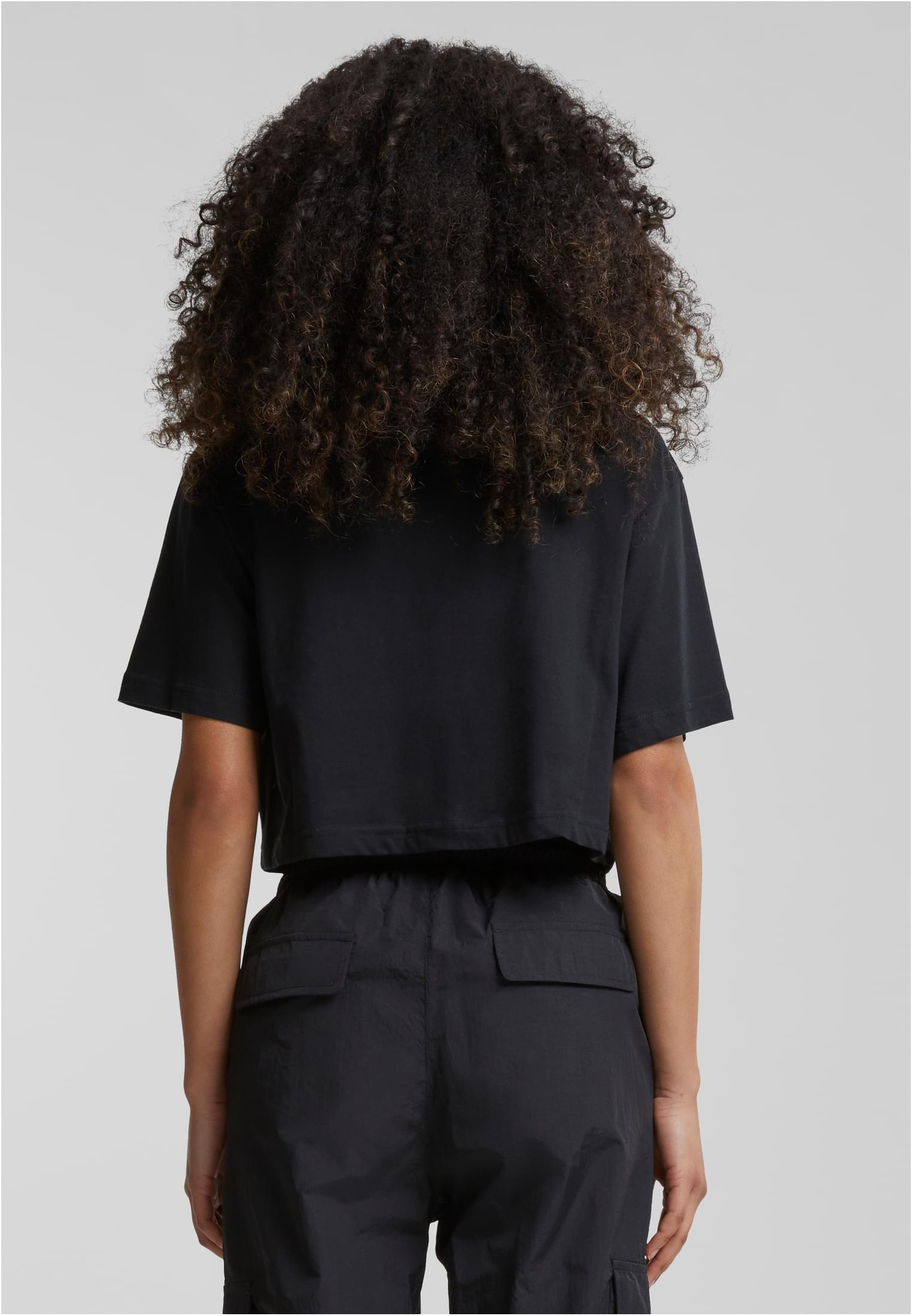 Modell sedd bakifrån, klädd i en svart Ladies Short Oversized Tee och svarta byxor.