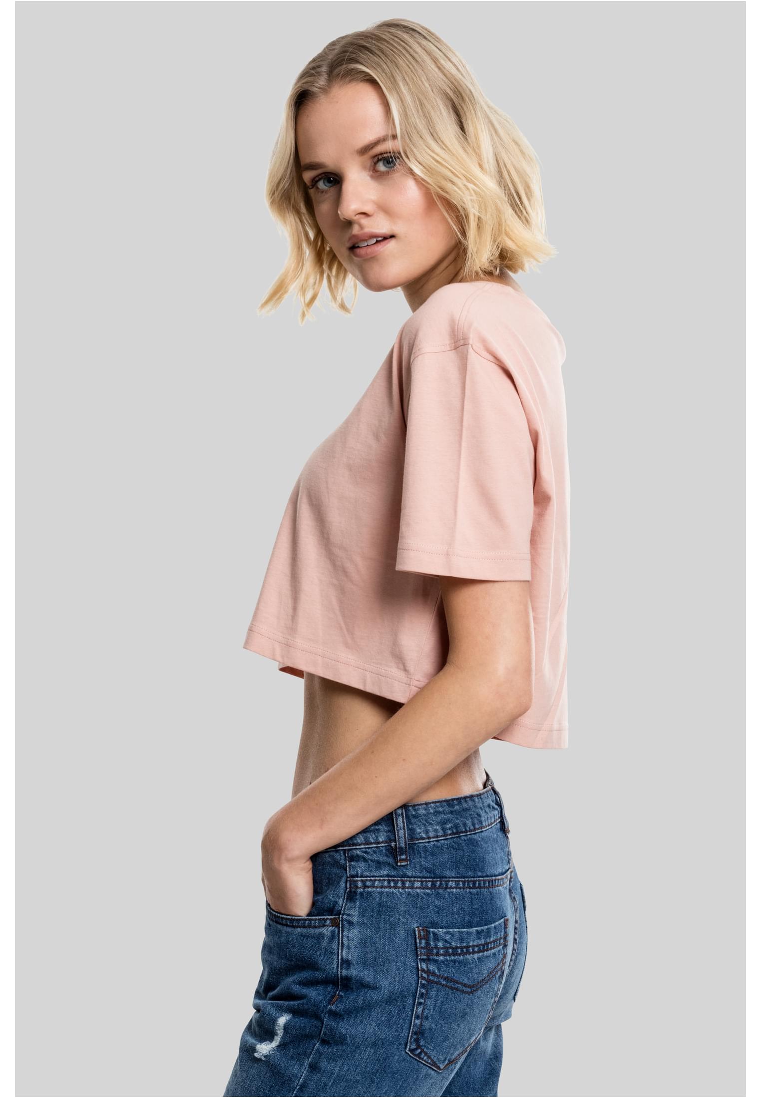 Sidovy av en kvinna i en kort, oversized t-shirt i terrakottafärg och blåjeans.