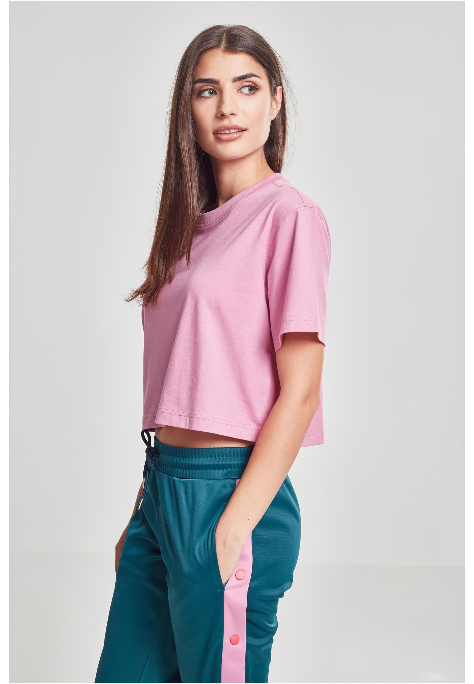 En kvinna, sedd från sidan, som bär en kort, oversized t-shirt i terrakotta och turkosa byxor.