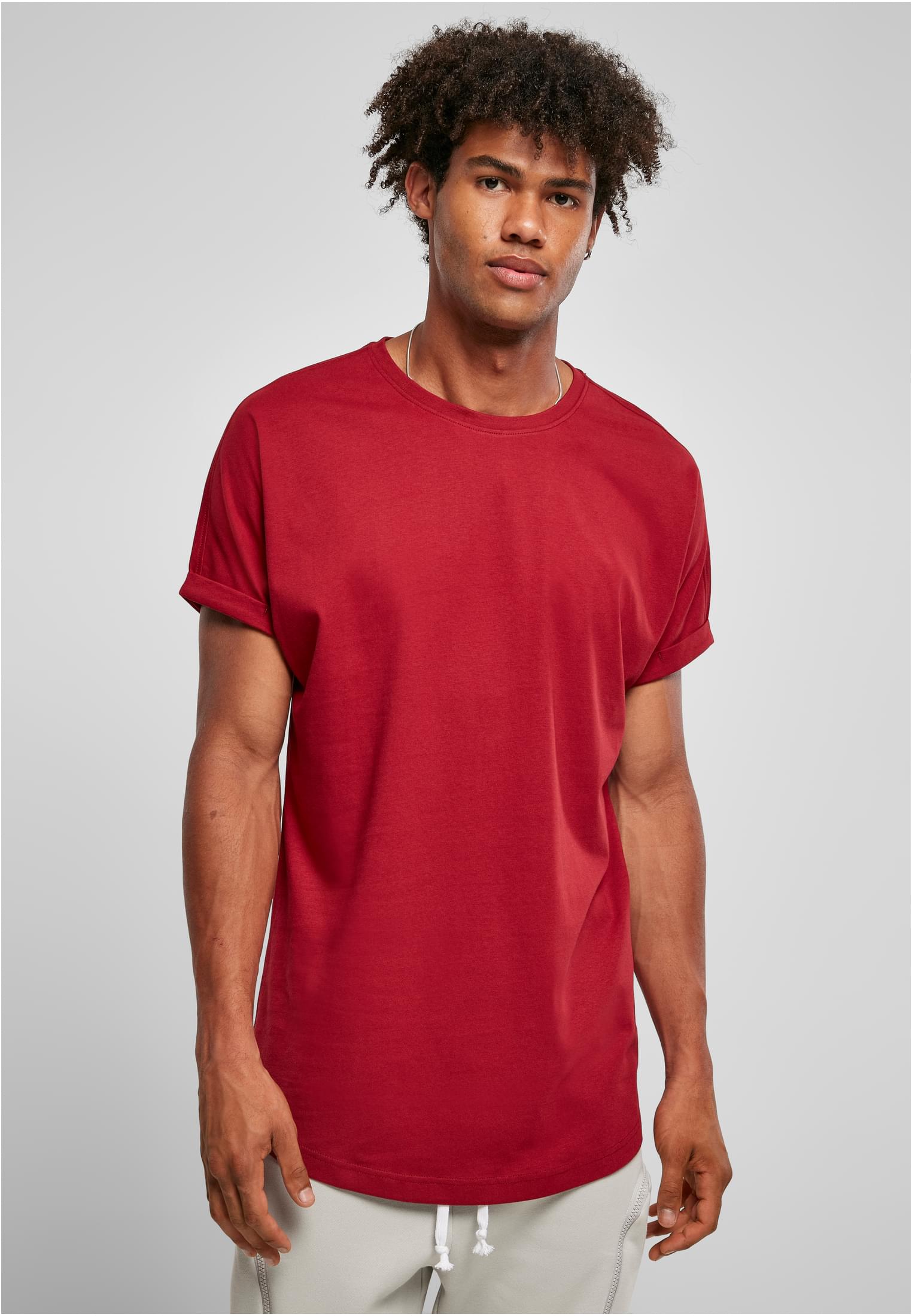 Manlig modell som bär en terrakottafärgad Long Shaped Turnup Tee med uppvikta ärmar.