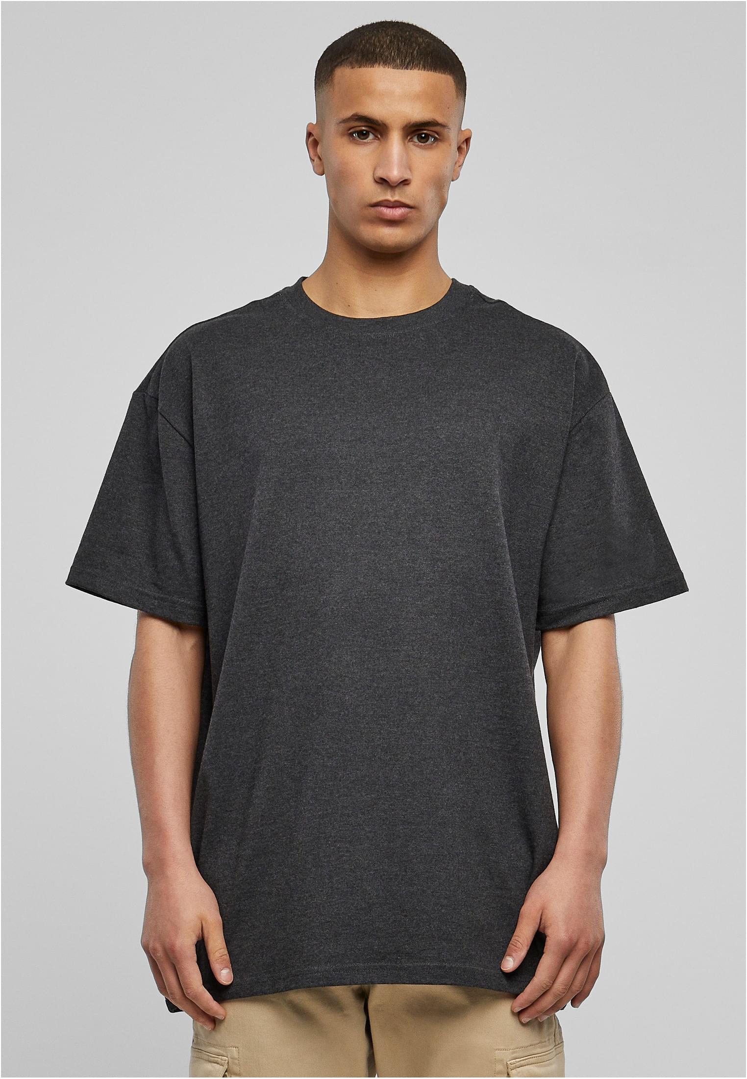 Manlig modell som bär en mörkgrå oversized t-shirt, sedd framifrån mot en ljusgrå bakgrund.