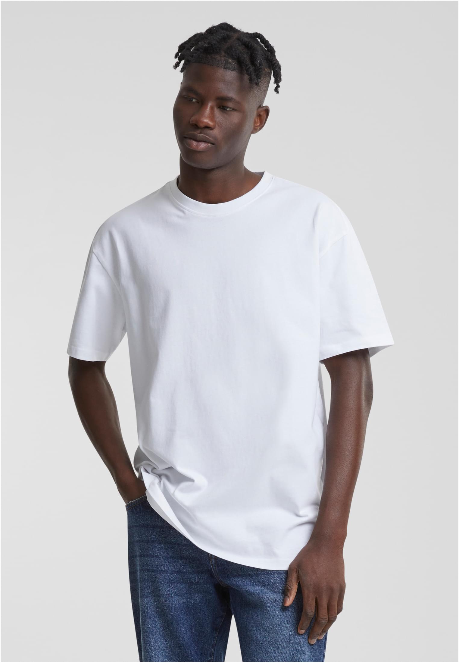 En manlig modell som bär en vit oversized t-shirt och blåa jeans.