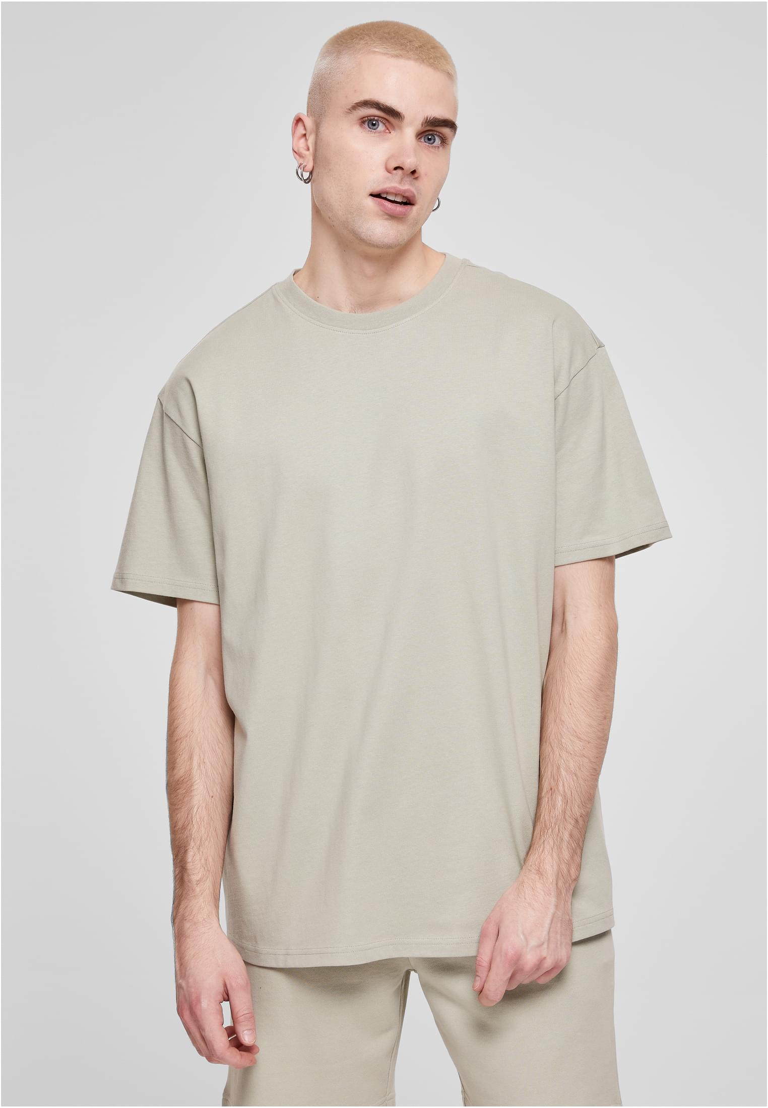Manlig modell med blont hår bär en ljusgrön oversized t-shirt mot en ljusgrå bakgrund.
