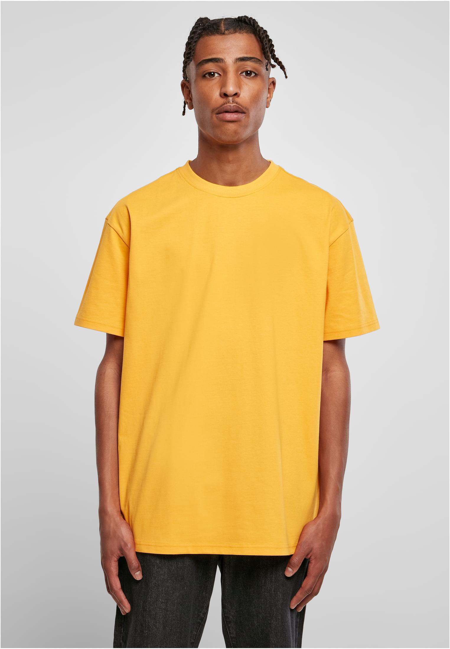 En manlig modell bär en gul Heavy Oversized Tee, fotograferad framifrån.