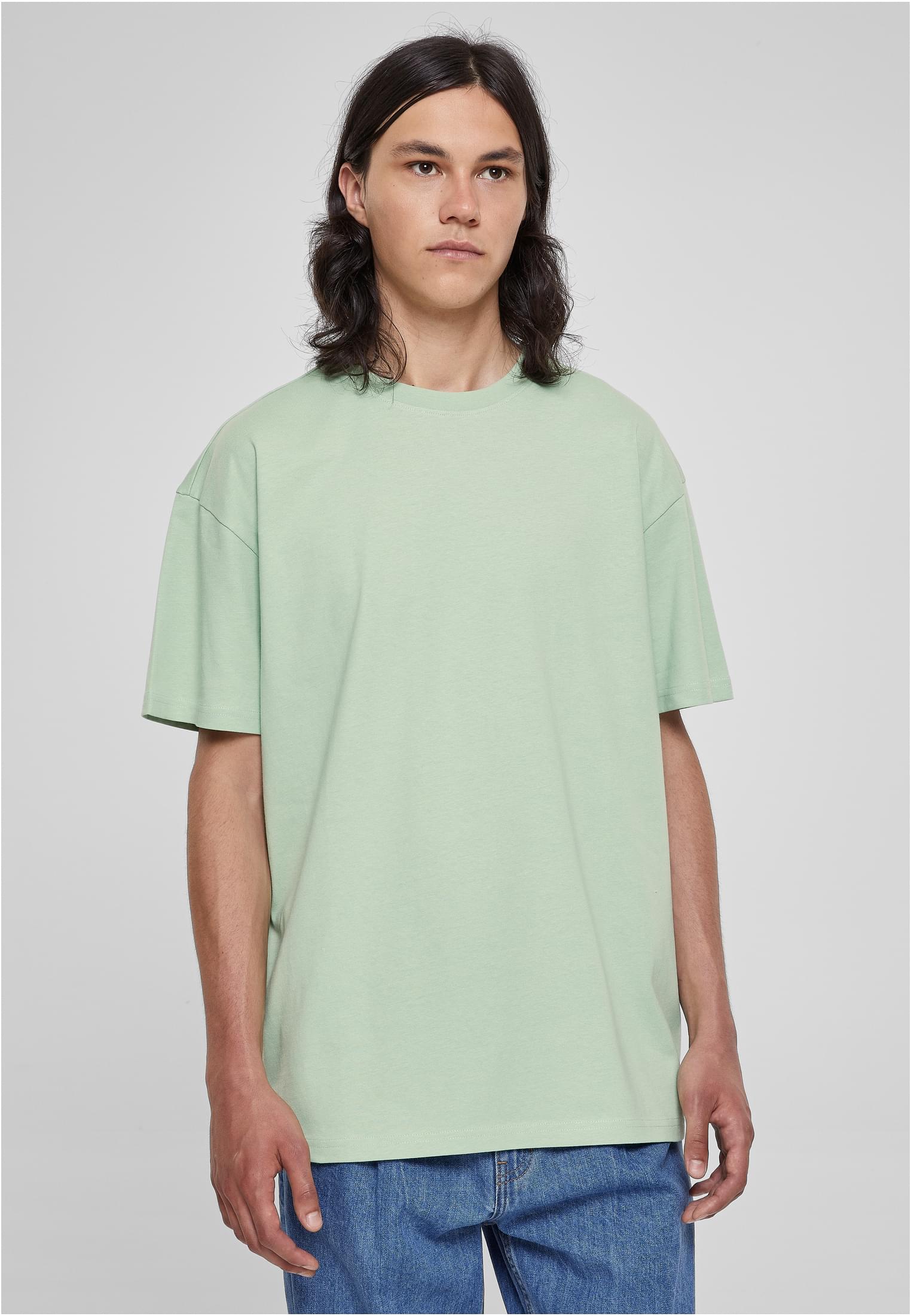 En manlig modell med långt hår som bär en ljusgrön Heavy Oversized Tee.