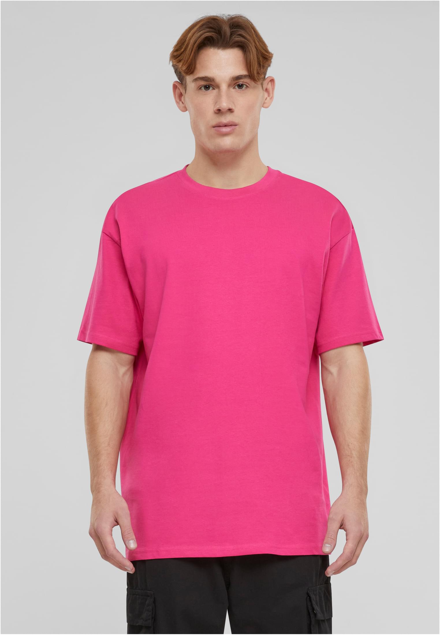 En manlig modell bär en rosa Heavy Oversized Tee framifrån mot en ljusgrå bakgrund.