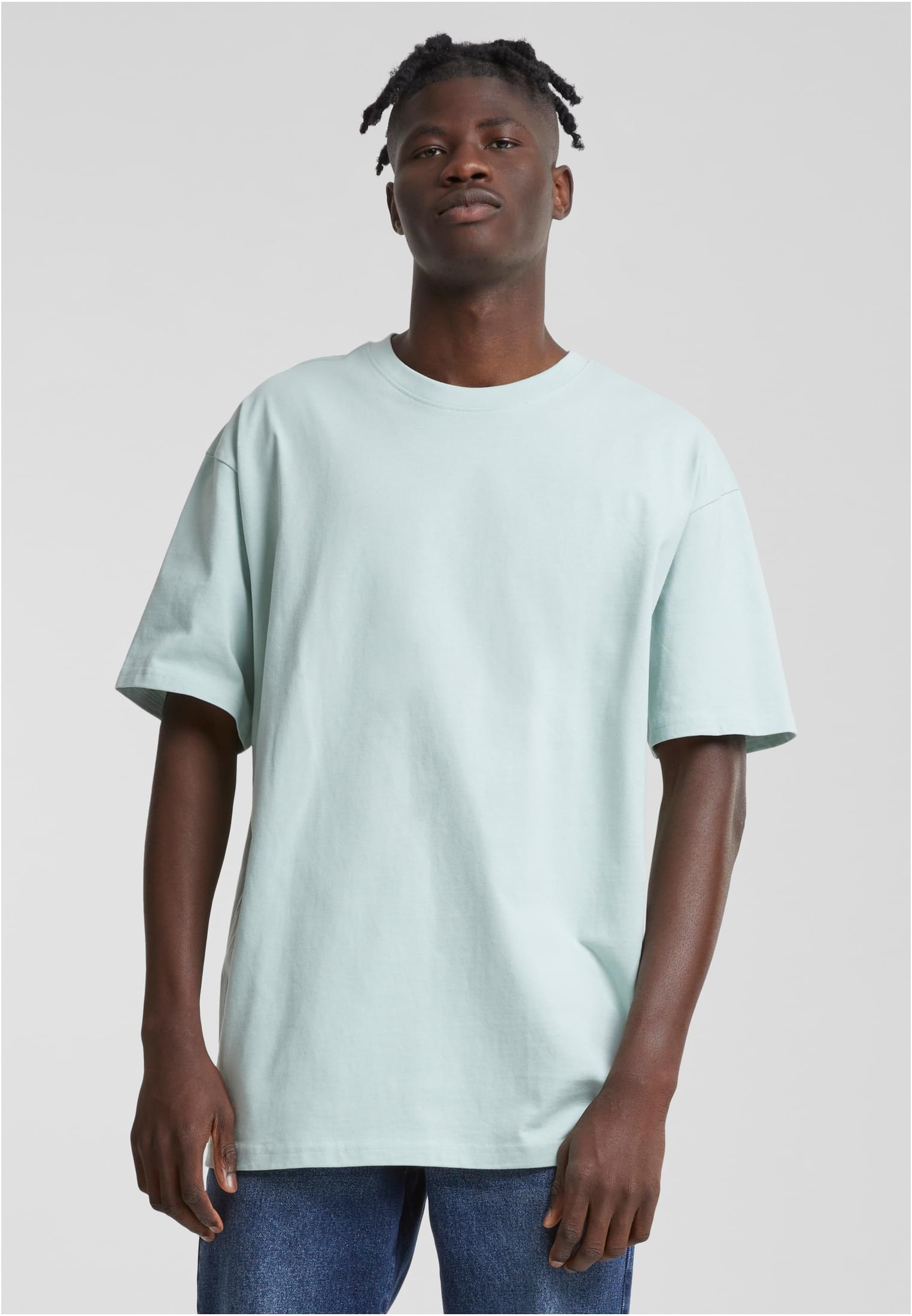 Manlig modell poserar i en oversized t-shirt i färgen frostmint mot en grå bakgrund.