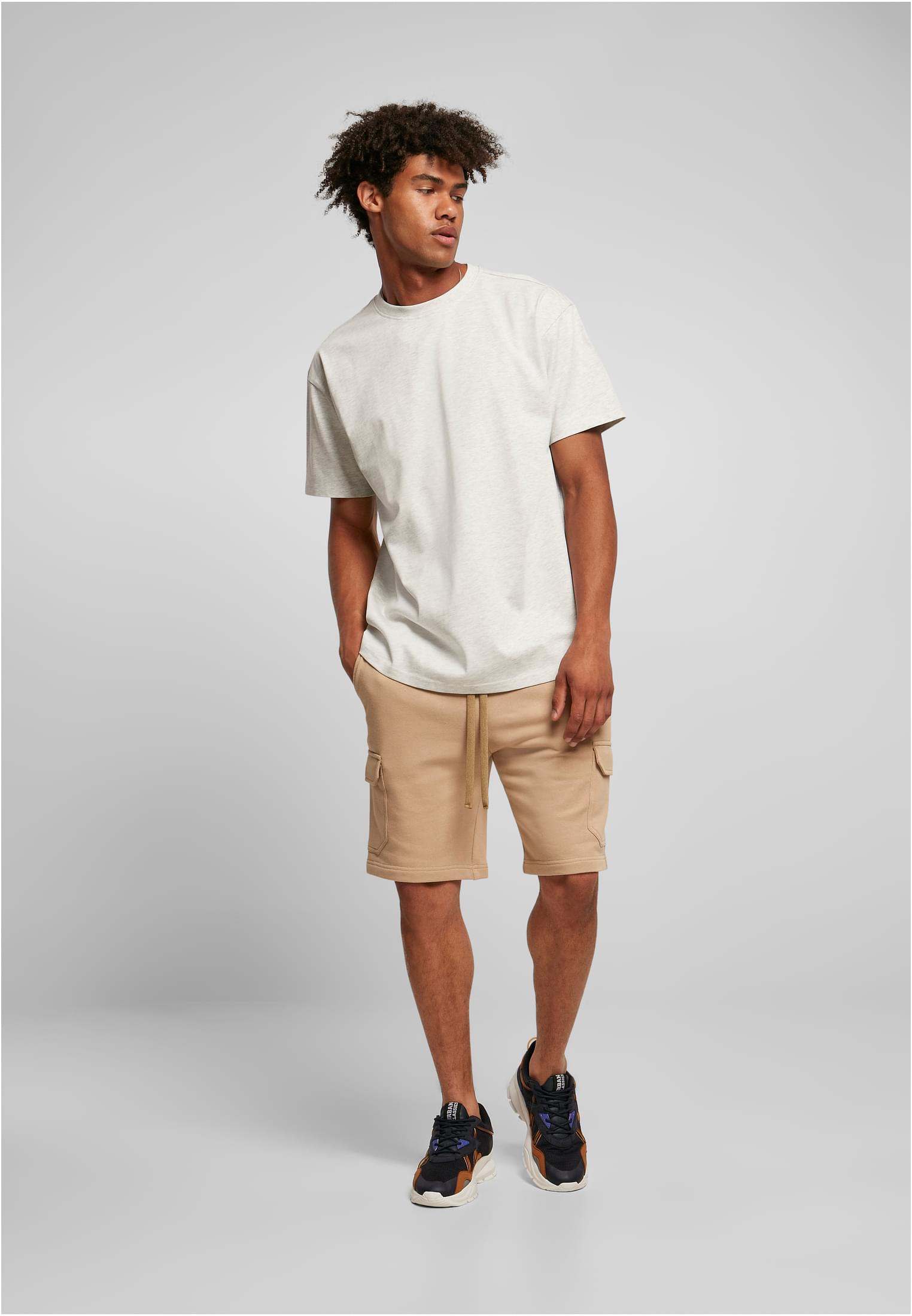 Manlig modell som poserar i en ljusmelerad oversized t-shirt och beiga shorts.