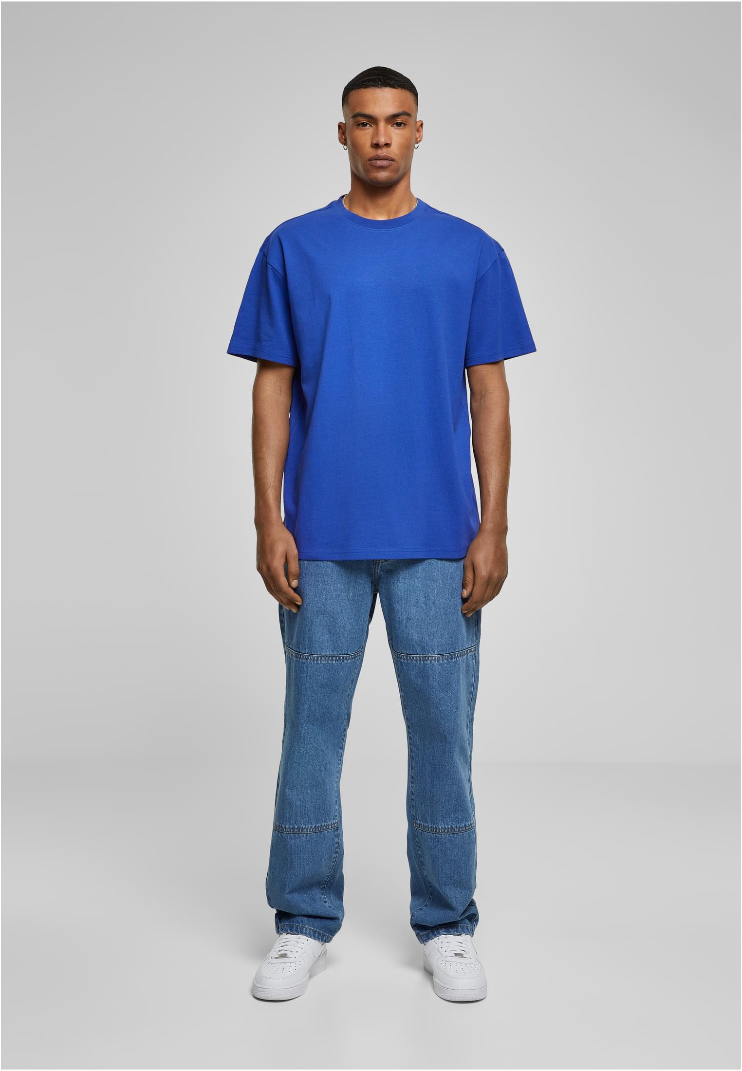 Manlig modell i helfigur som bär en blå Heavy Oversized T-shirt, jeans och vita sneakers.
