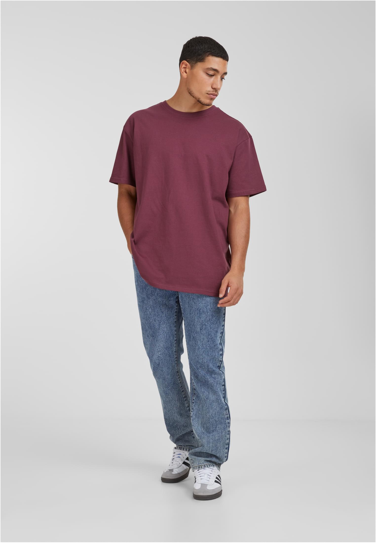 Manlig modell som bär en vinröd UC Heavy Oversized T-shirt och blå jeans.