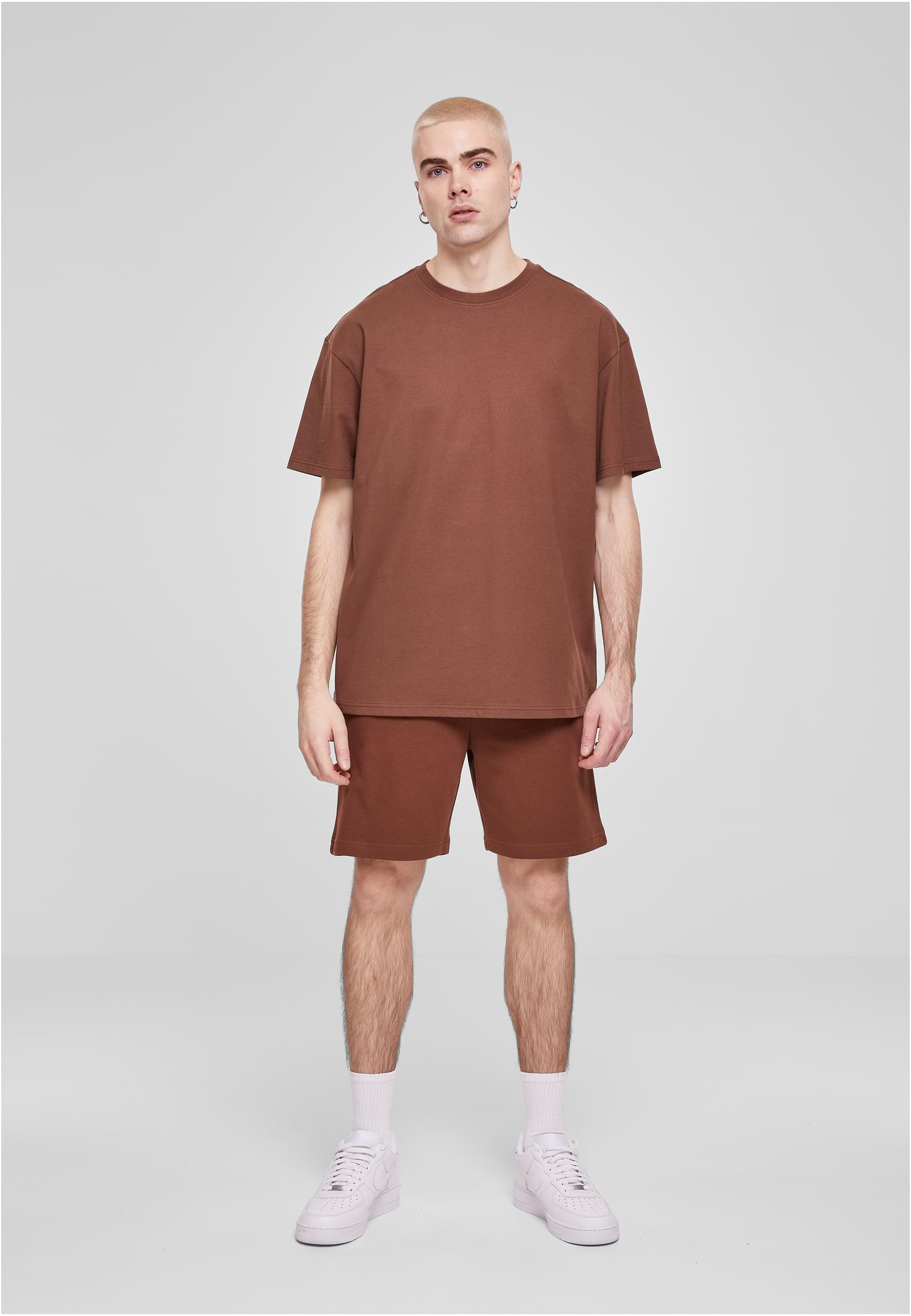 Manlig modell i en brun Heavy Oversized Tee från Urban Classics och matchande shorts, fotograferad framifrån.