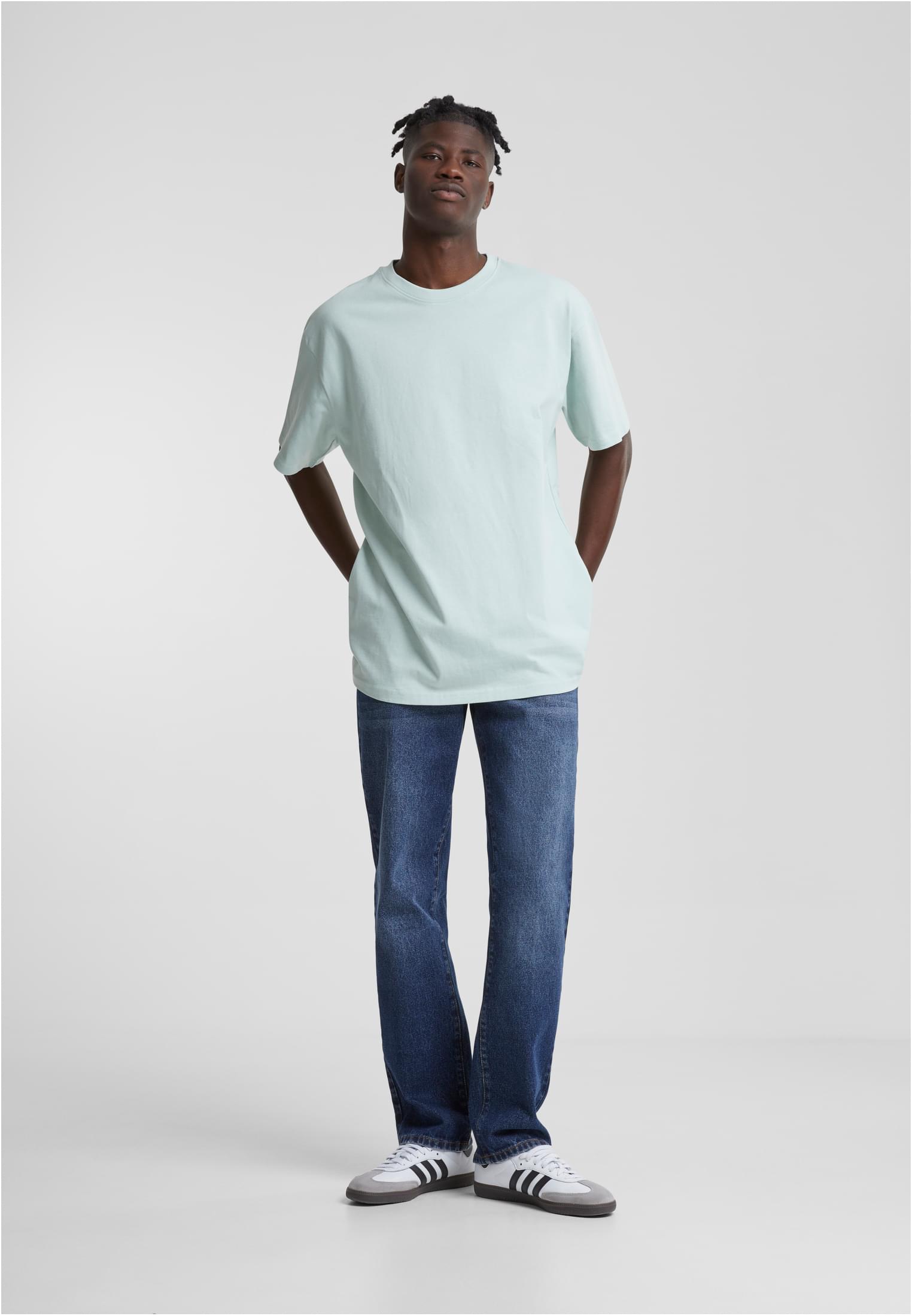 Helbild på en man som bär en mintgrön Heavy Oversized Tee, mörkblå jeans och vita sneakers.