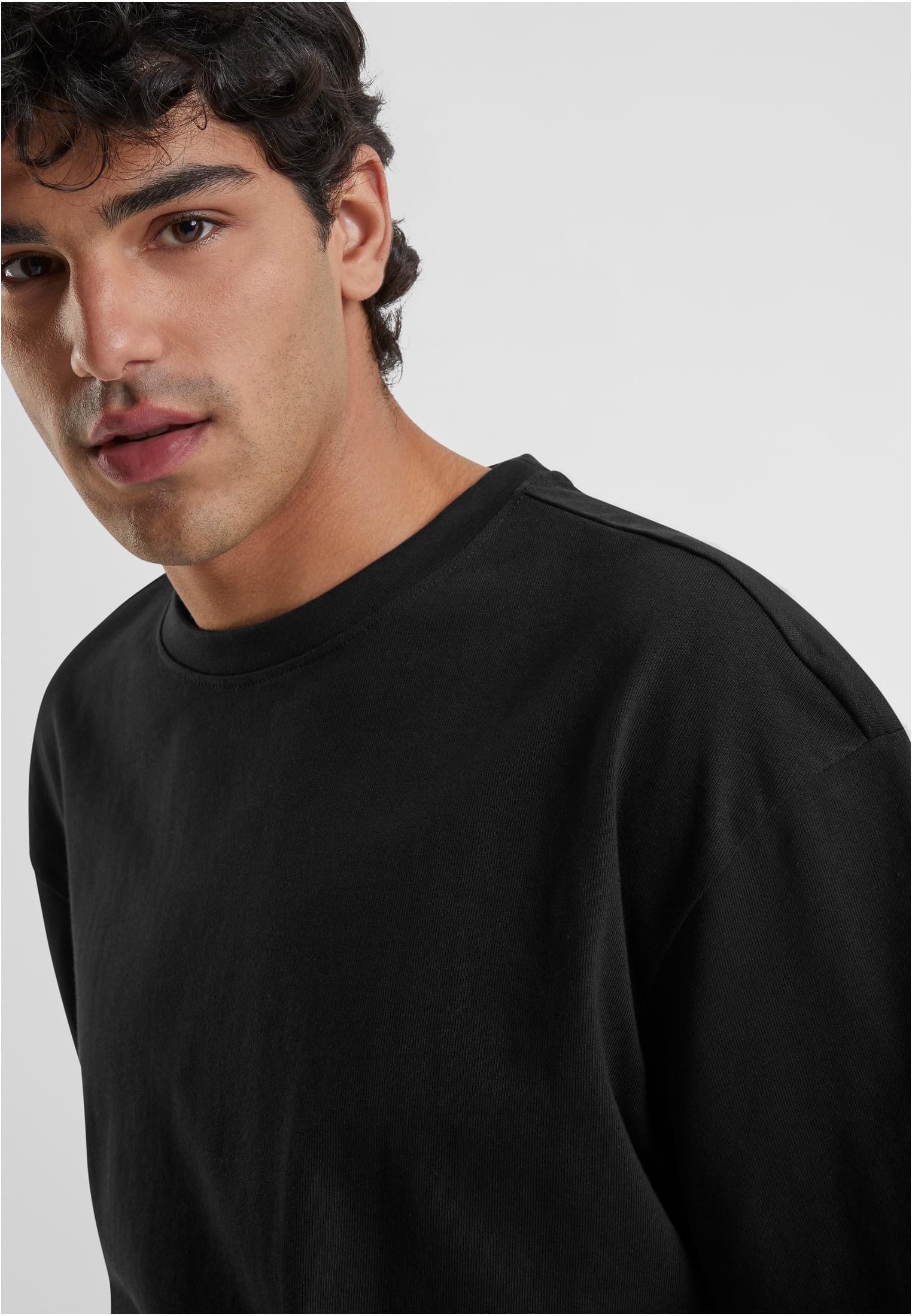 Närbild på en man som bär en svart Heavy Oversized Tee.