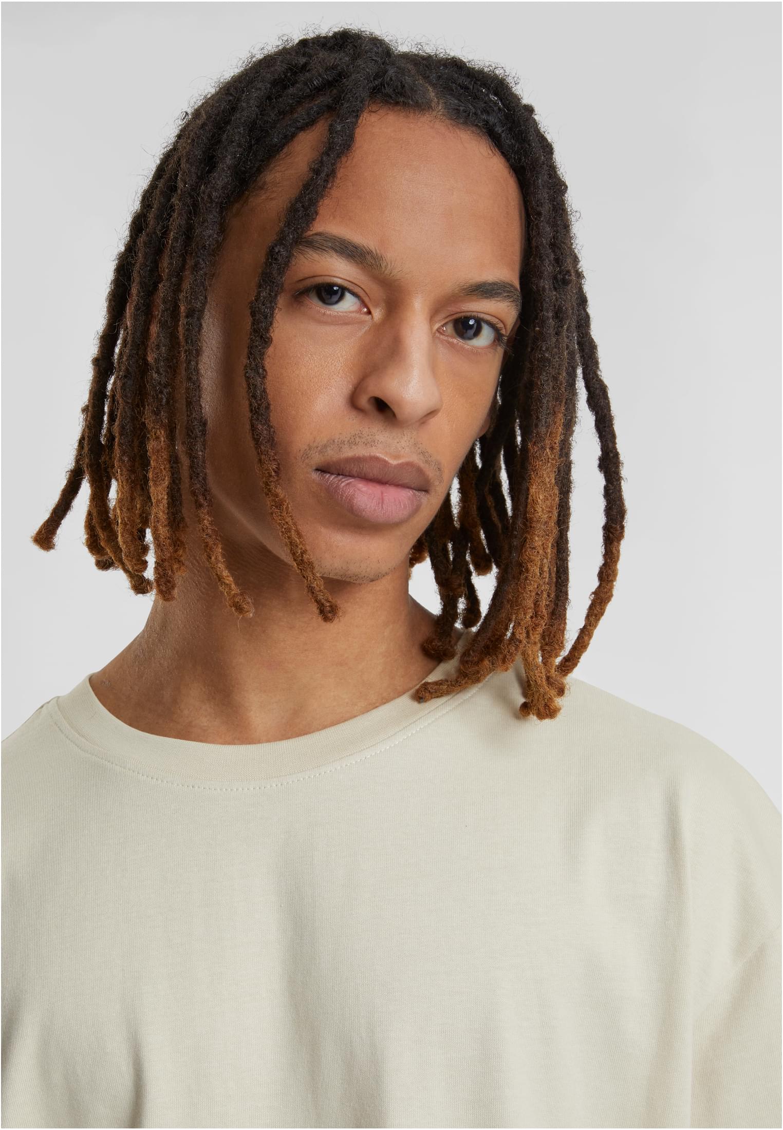 Närbild på en manlig modell med dreadlocks som bär en UC Heavy Oversized Tee i frostmint.