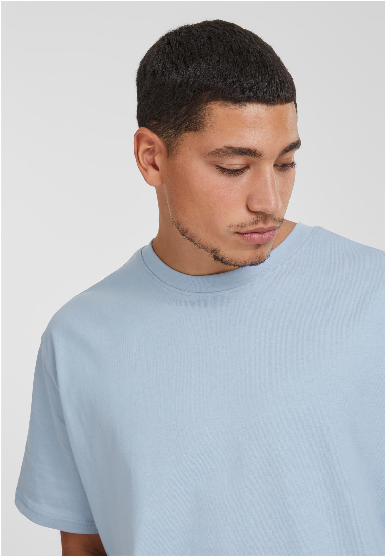 Närbild på en man som bär en ljusblå Heavy Oversized T-shirt från Urban Classics.