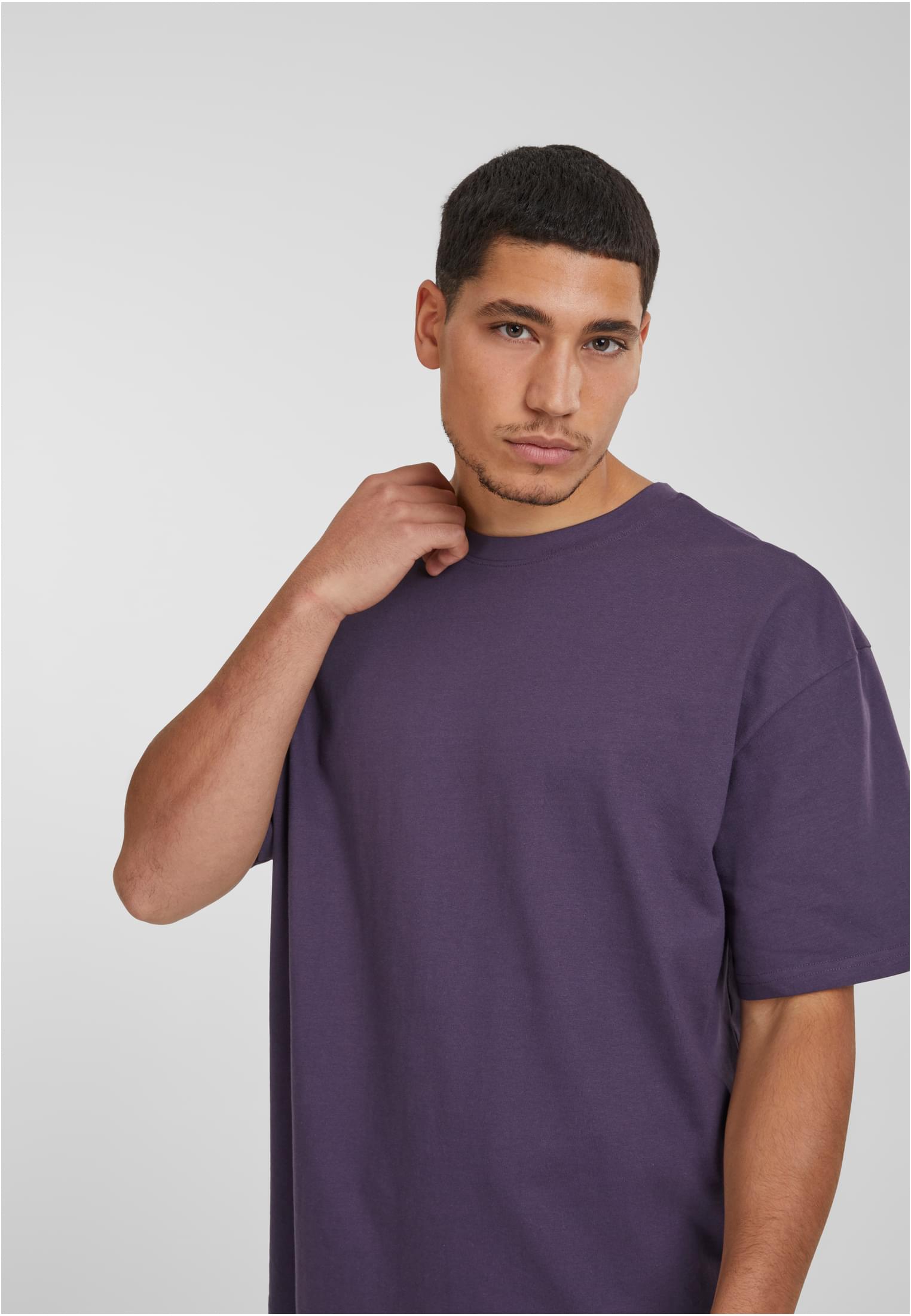 Närbild på en man som bär en lila Heavy Oversized Tee från Urban Classics.