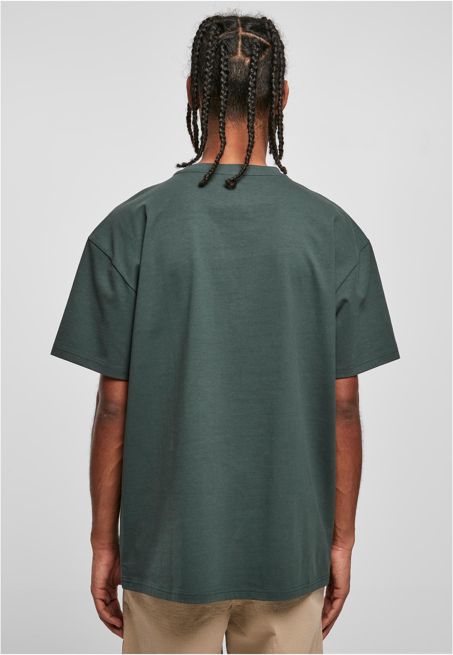 Baksidan av en manlig modell som bär en mörkgrön Heavy Oversized Tee.
