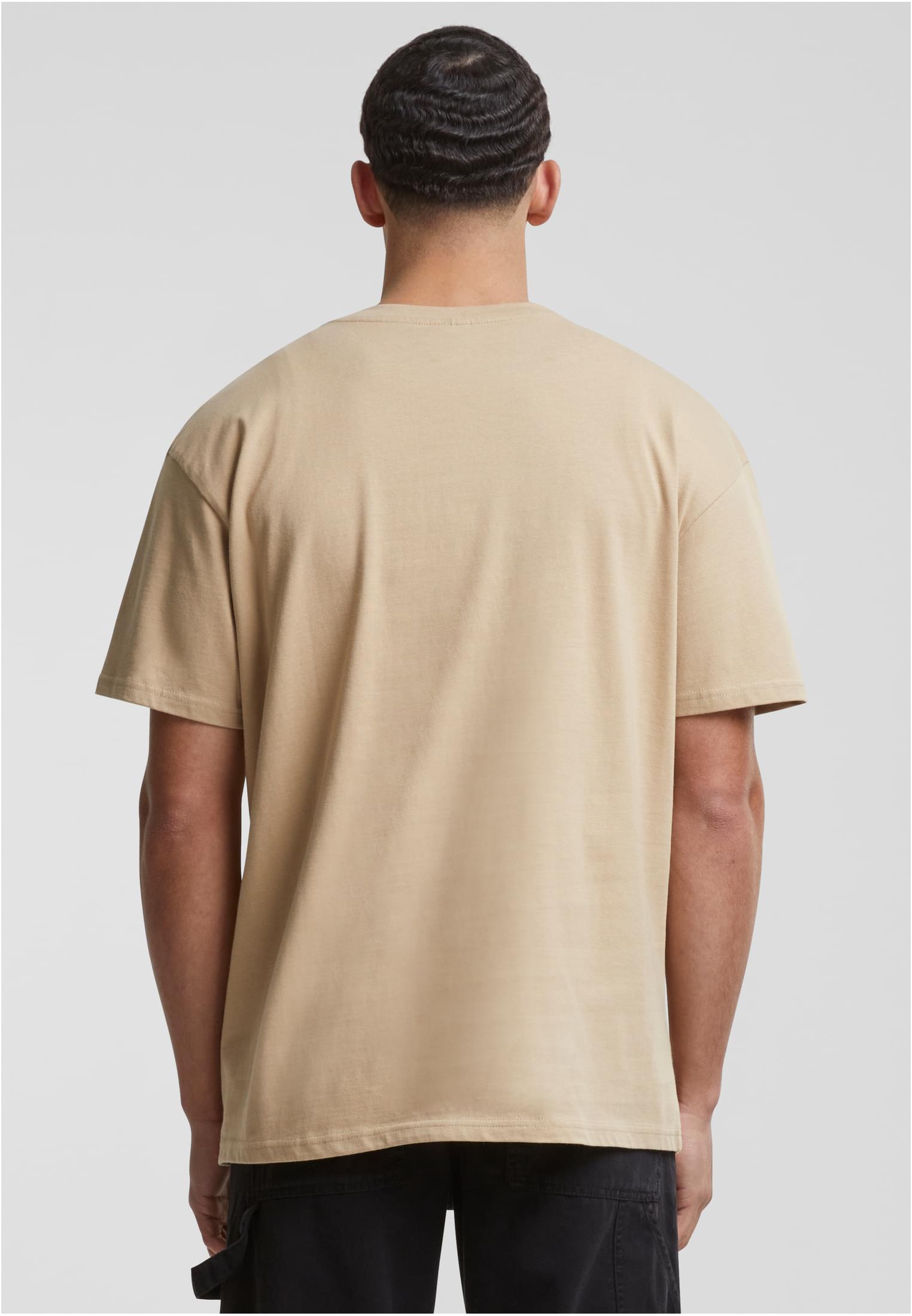 Baksidan av en man som bär en beige oversized t-shirt.