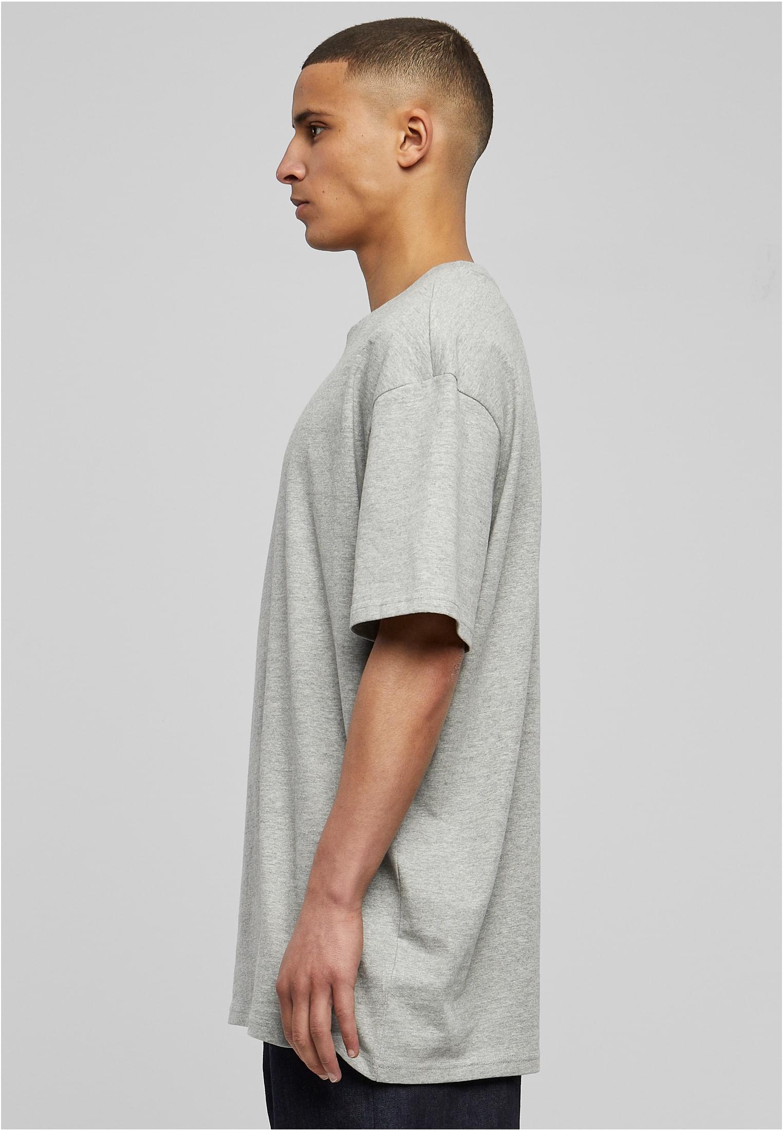 Manlig modell sedd från sidan, bärandes en grå Heavy Oversized Tee.