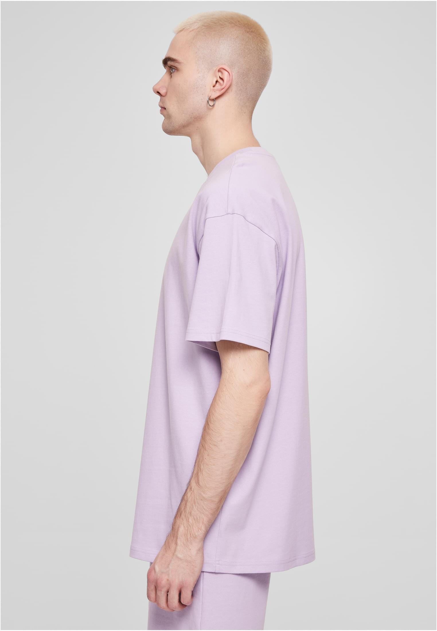 Manlig modell i profil som bär en ljuslila Heavy Oversized T-shirt.