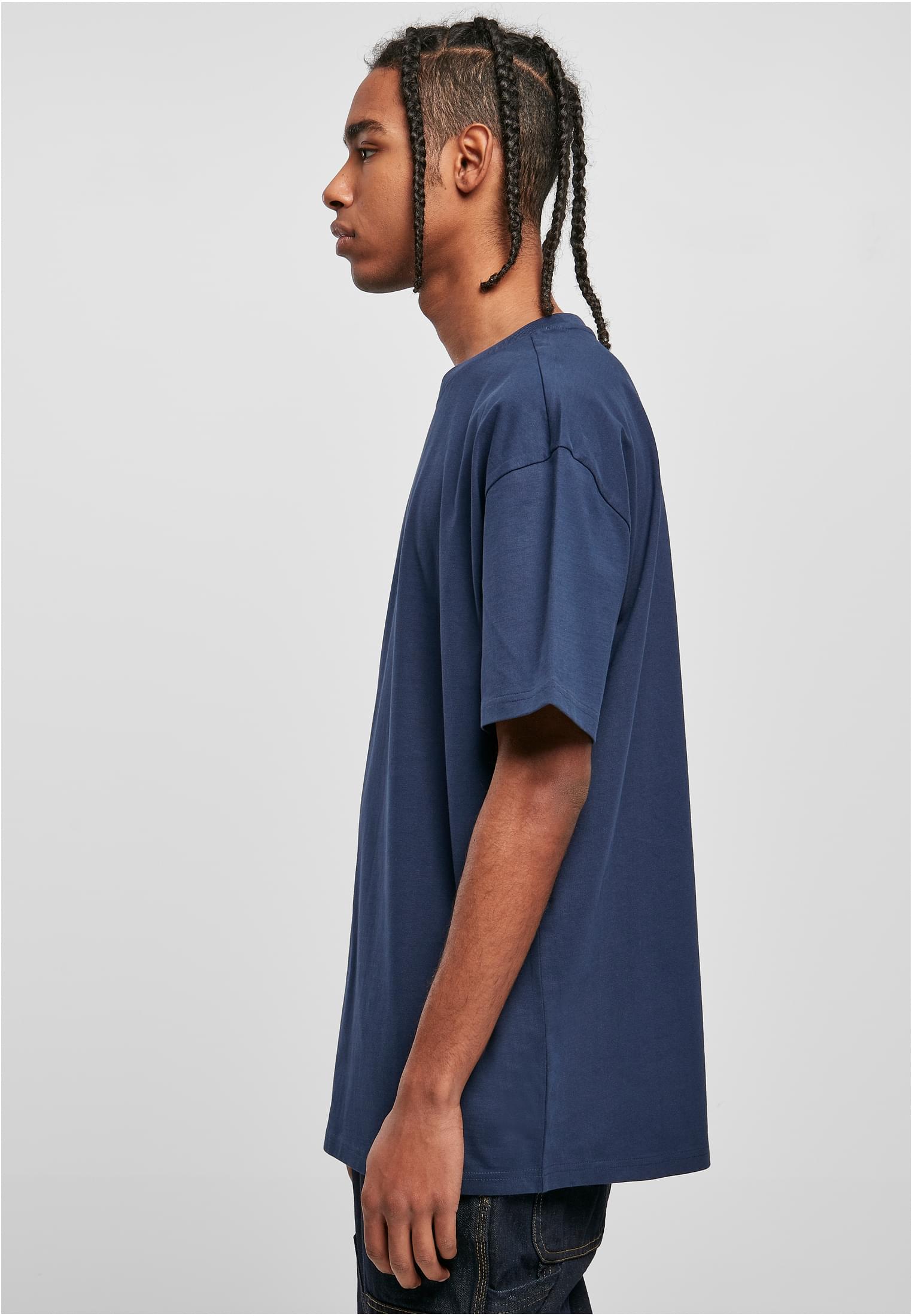 Sidovy av en manlig modell med flätat hår som bär en Heavy Oversized Tee i frostmint.