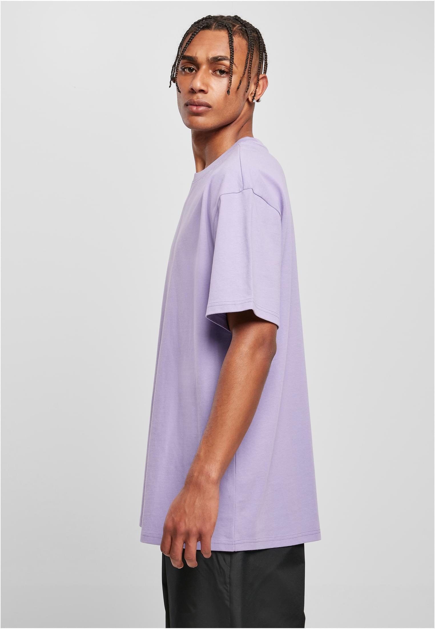 Man med flätat hår, fotograferad från sidan, bär en ljuslila Heavy Oversized Tee.