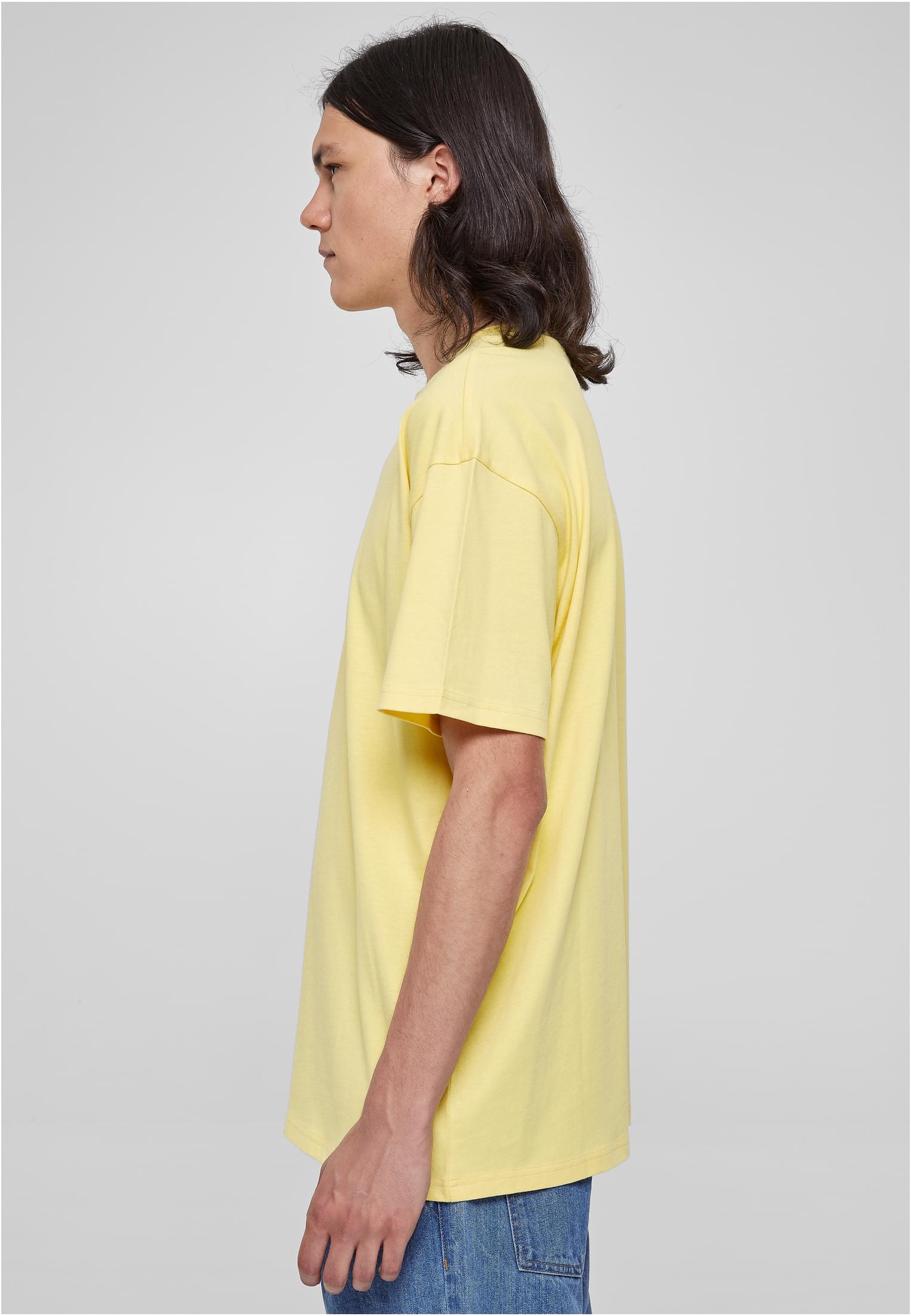 Manlig modell, fotograferad från sidan, bär en ljusgul Heavy Oversized Tee.