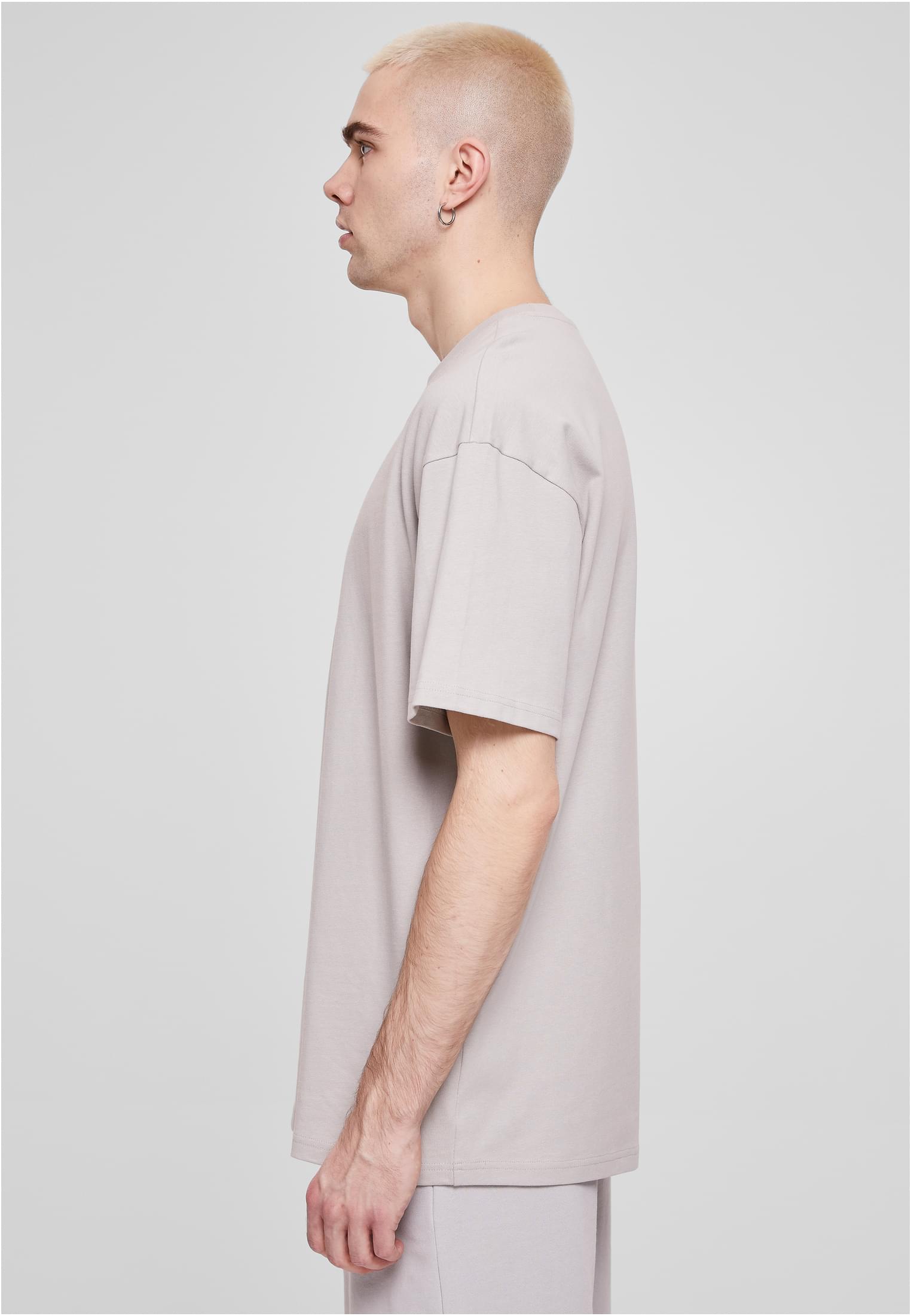 Sidovy av en man som visar passformen på en ljusgrå Heavy Oversized Tee.