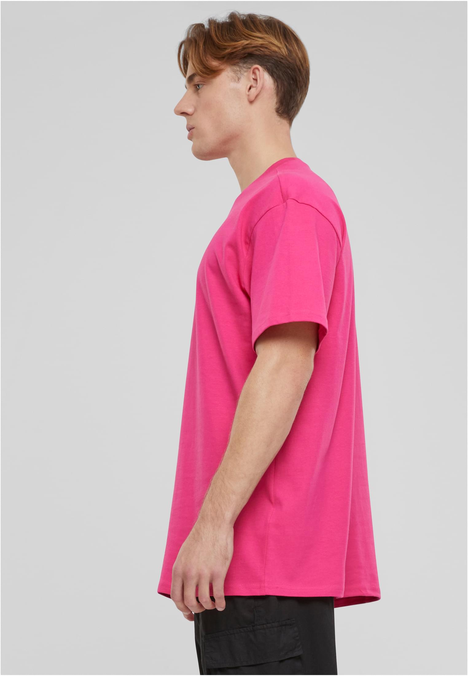 En man i en rosa oversized t-shirt, sedd från sidan.