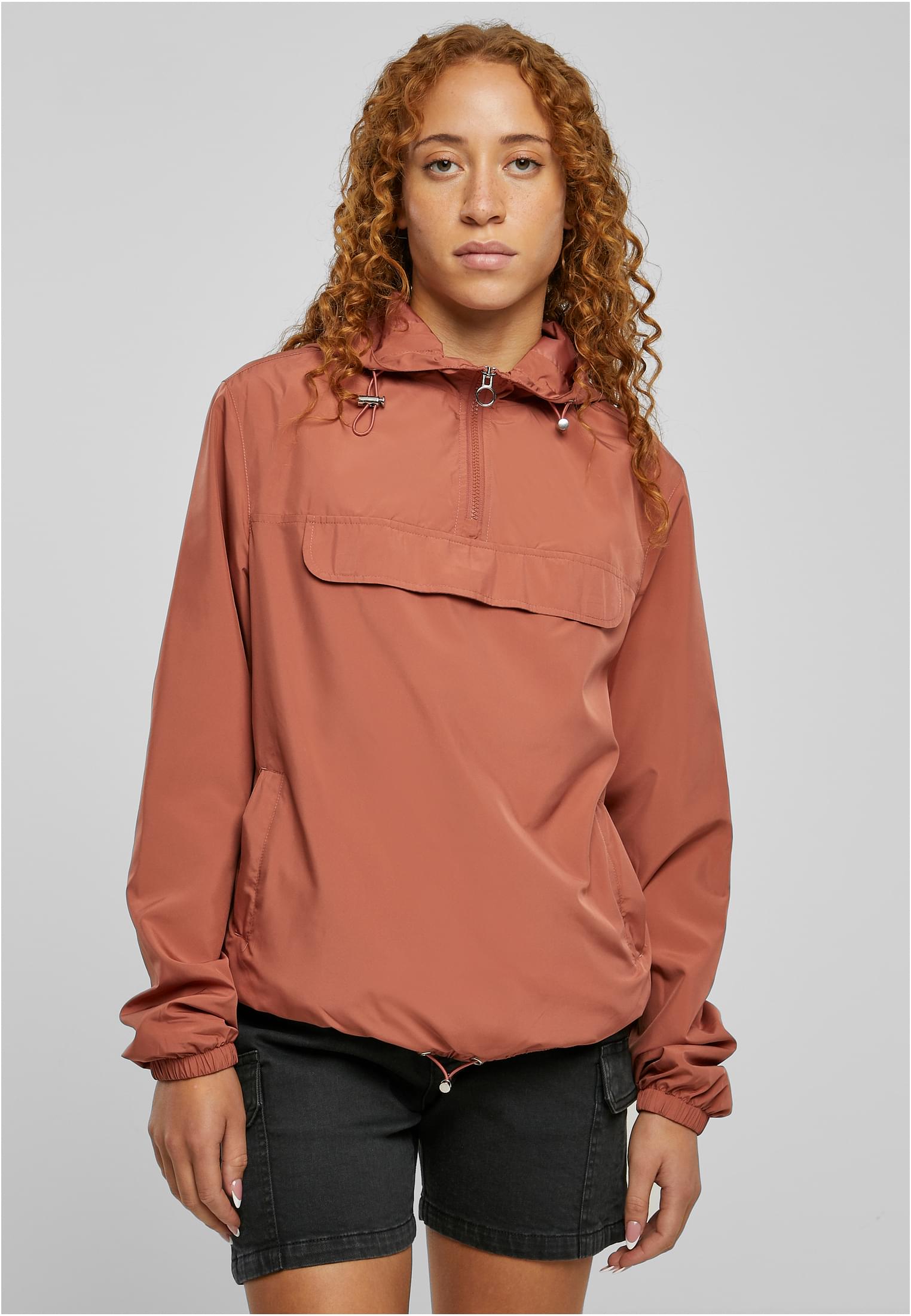 En kvinnlig modell bär den rostfärgade vindjackan UC Ladies Basic Pull Over Jacket.