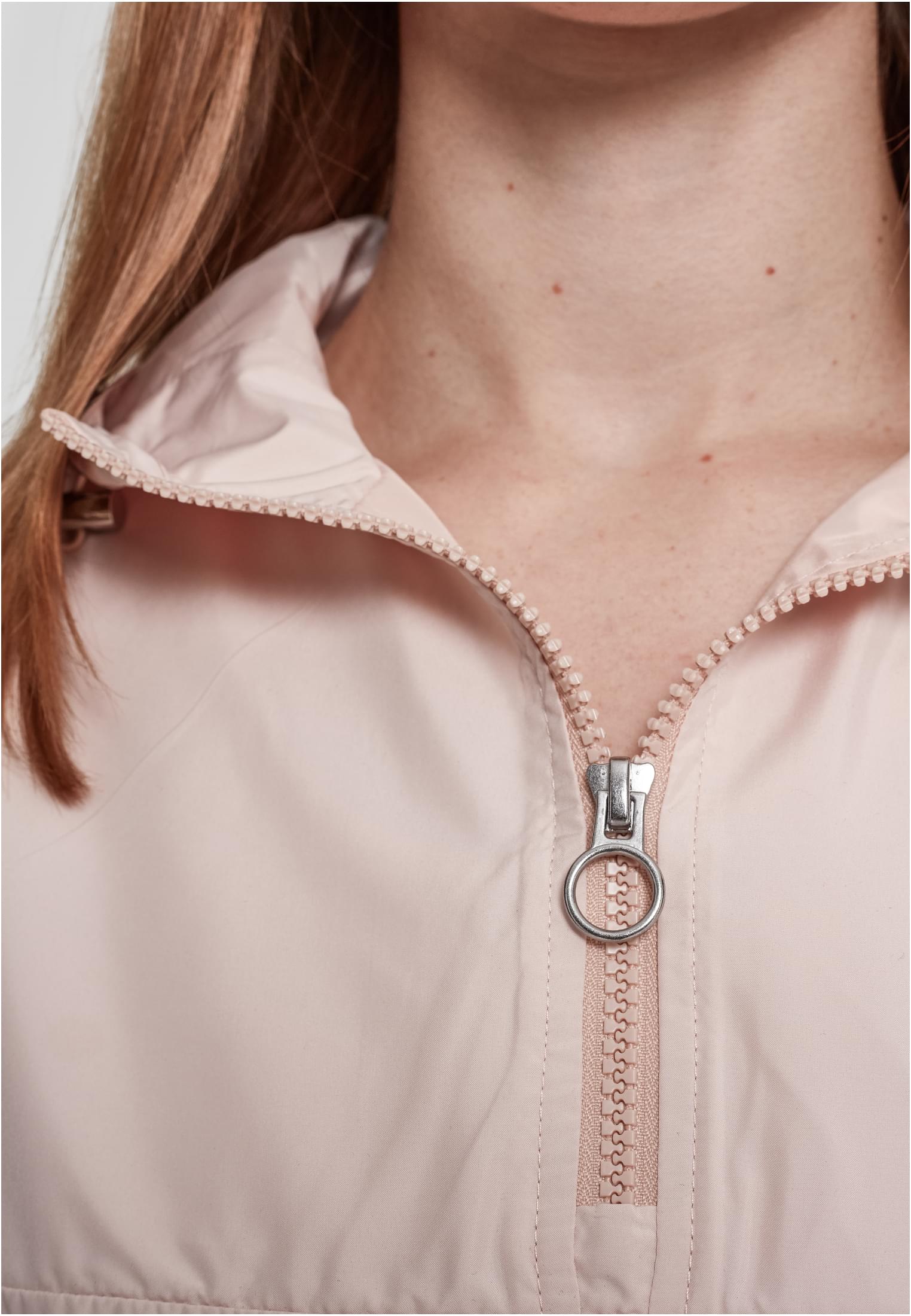 Närbild på en ljusrosa jacka med en silverfärgad dragkedja som har en stor ring som dragtapp.