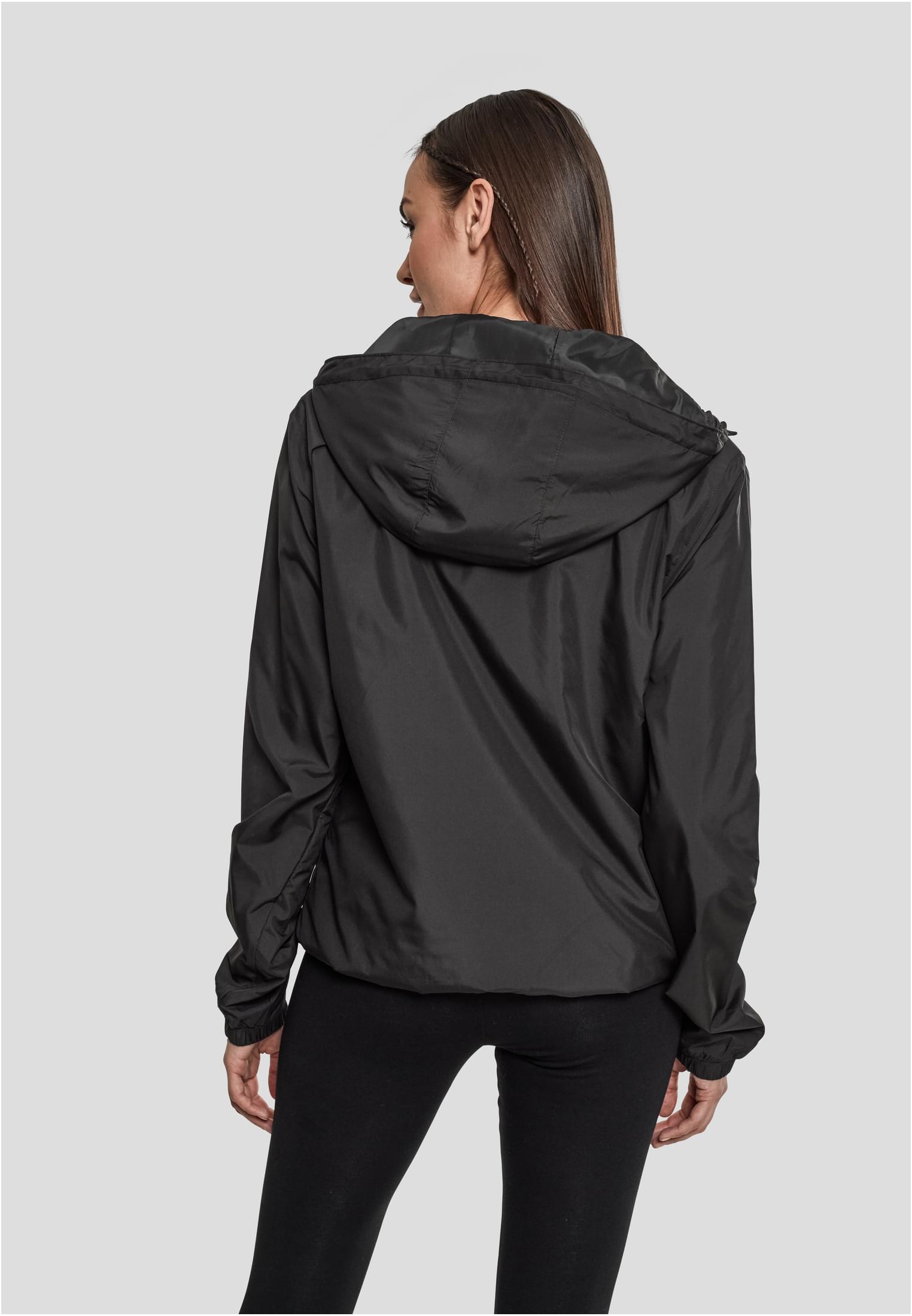 En kvinna som bär en svart Ladies Basic Pull Over Jacket, sedd bakifrån.