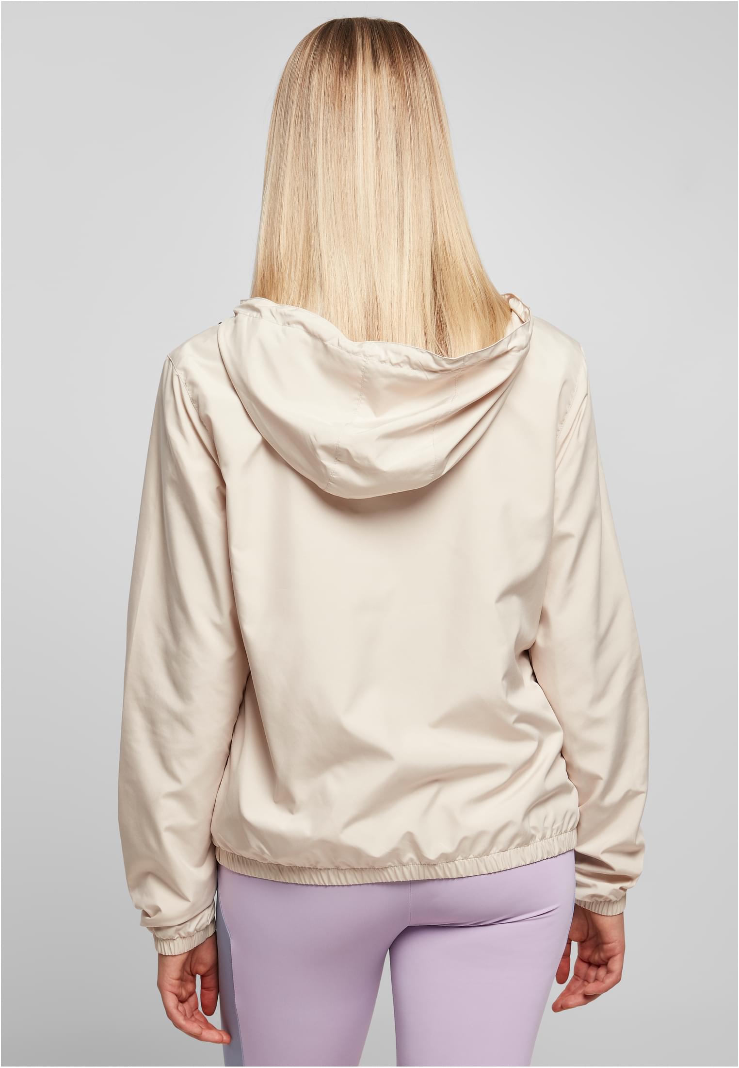 Kvinna sedd bakifrån som bär en beige Ladies Basic Pull Over Jacket och lila leggings.