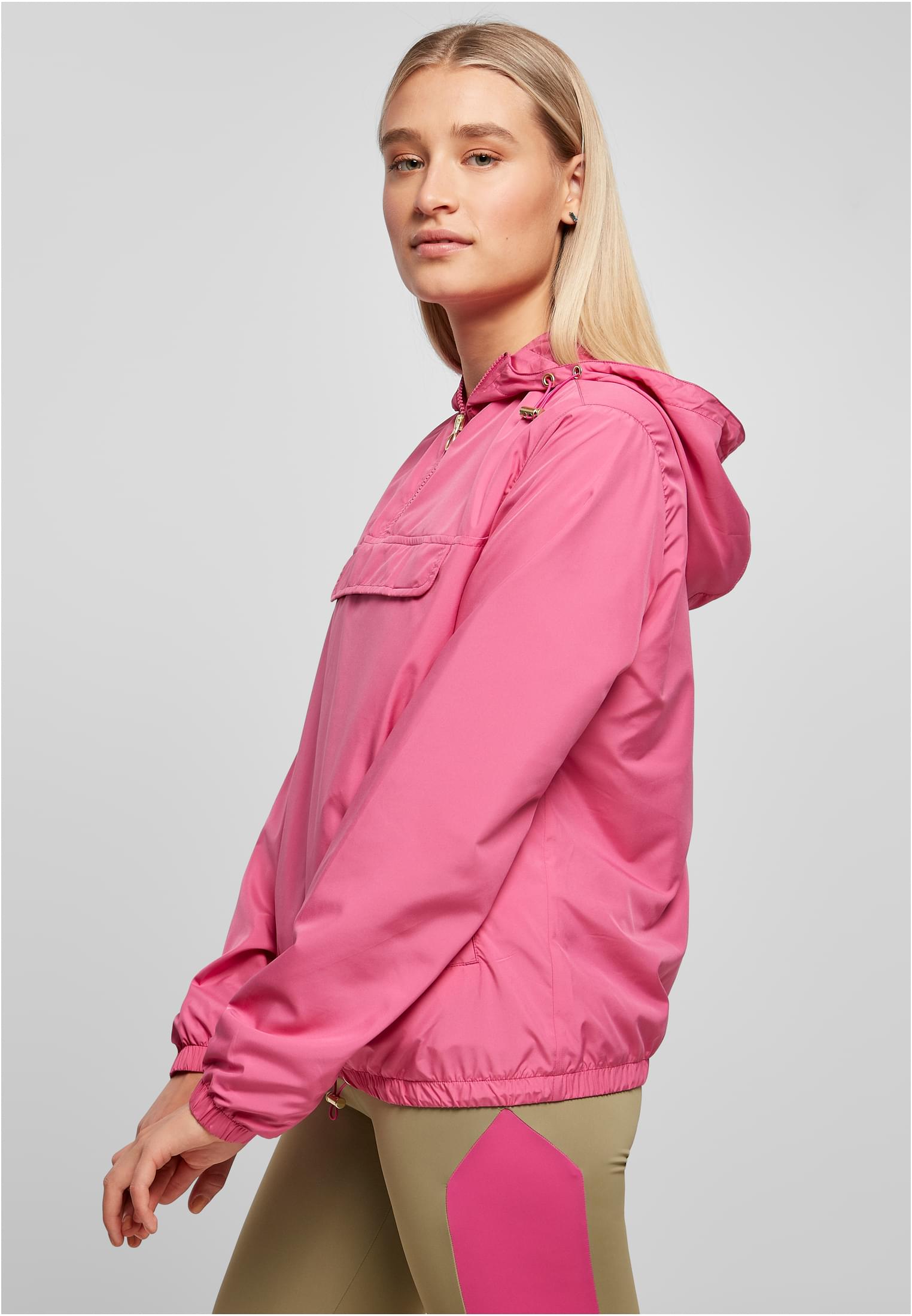 Kvinna i en rosa Ladies Basic Pull Over Jacket, fotograferad från sidan.