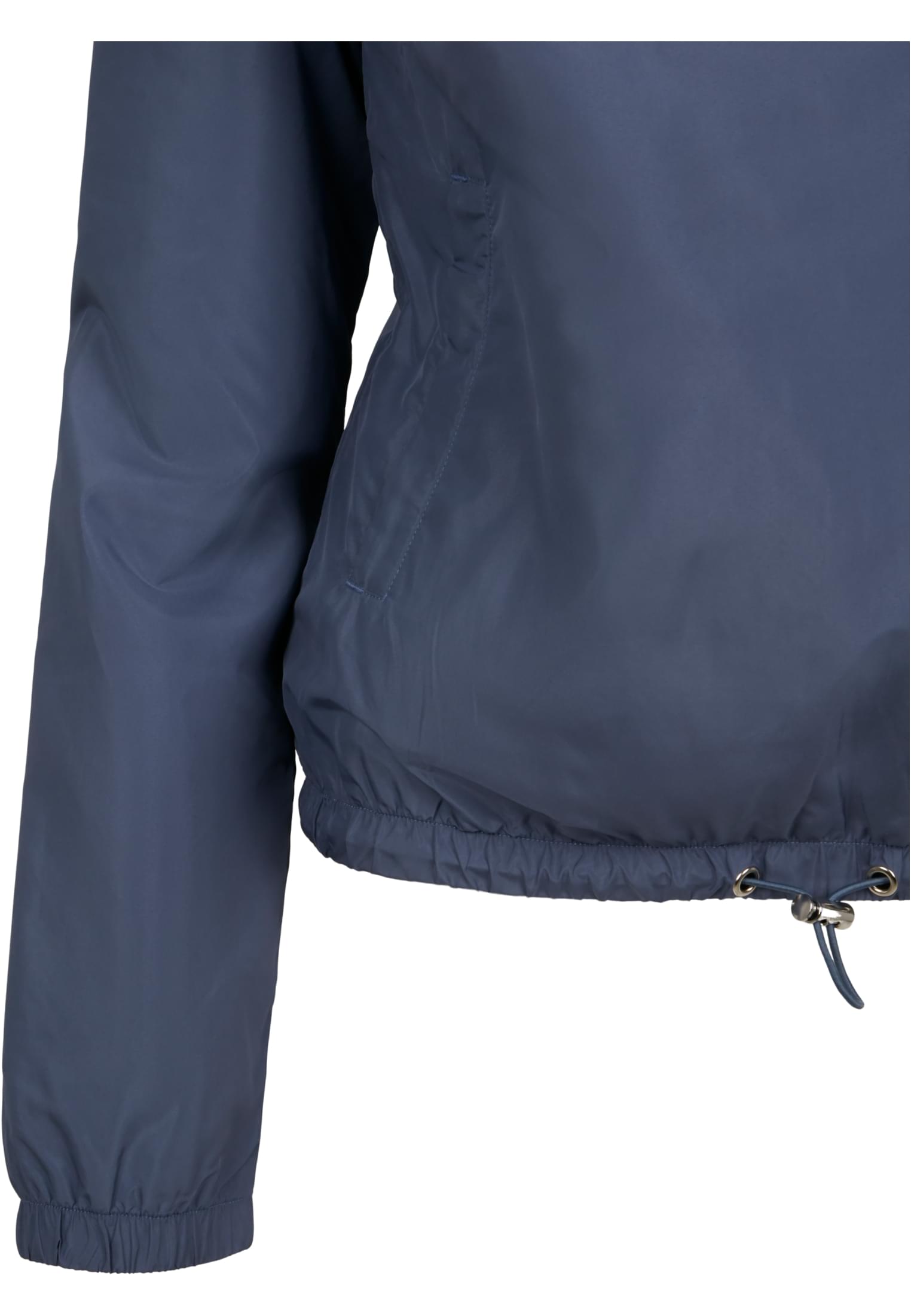 Detaljbild på sidan av en blå pulloverjacka för damer, som visar sidofickan och den justerbara dragskon i nederkanten.