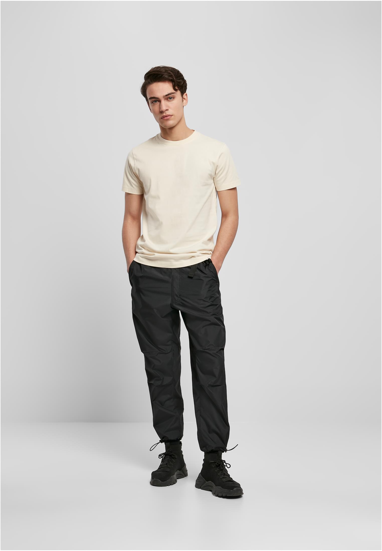 En man visar framsidan av en aprikosfärgad Basic Tee.