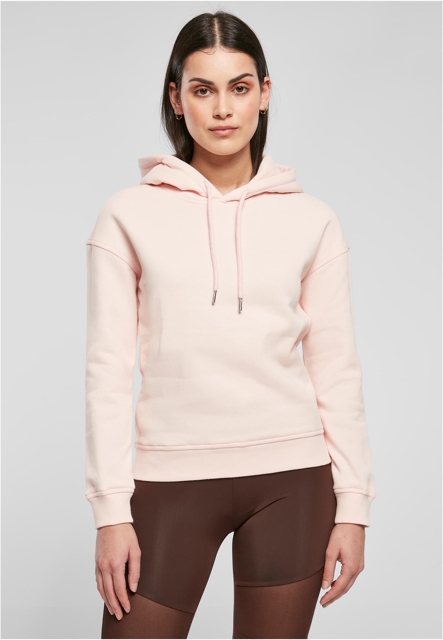 Kvinna sedd framifrån, bärandes en terrakottafärgad Ladies Organic Hoody.